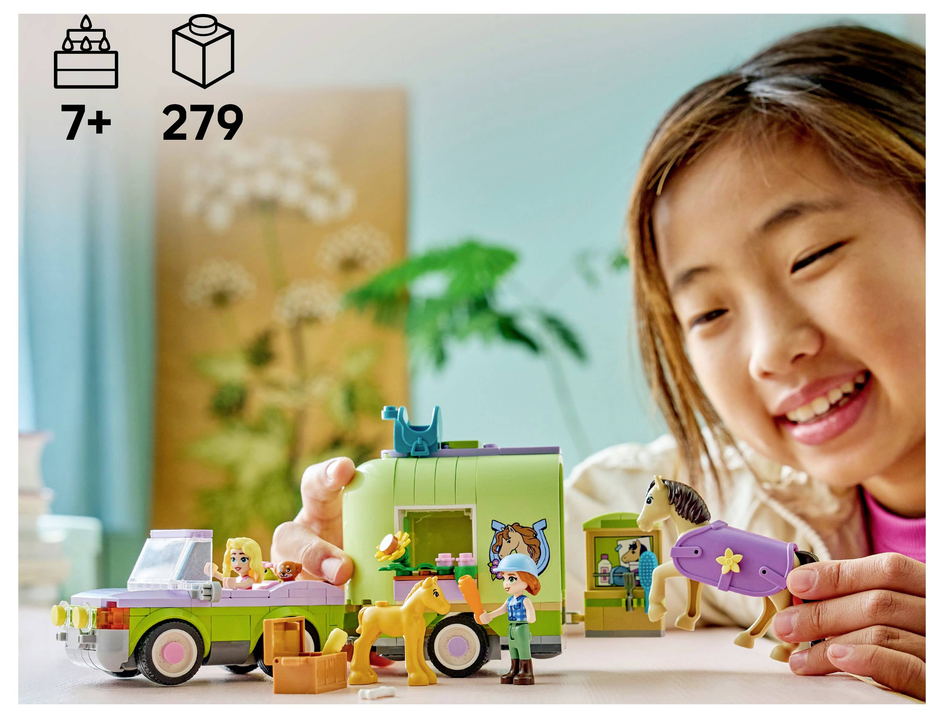 Ein Kind spielt mit einem LEGO-Set, das einen Pferdeanhänger und Figuren enthält, geeignet für Kinder ab 7 Jahren, mit 279 Teilen.
