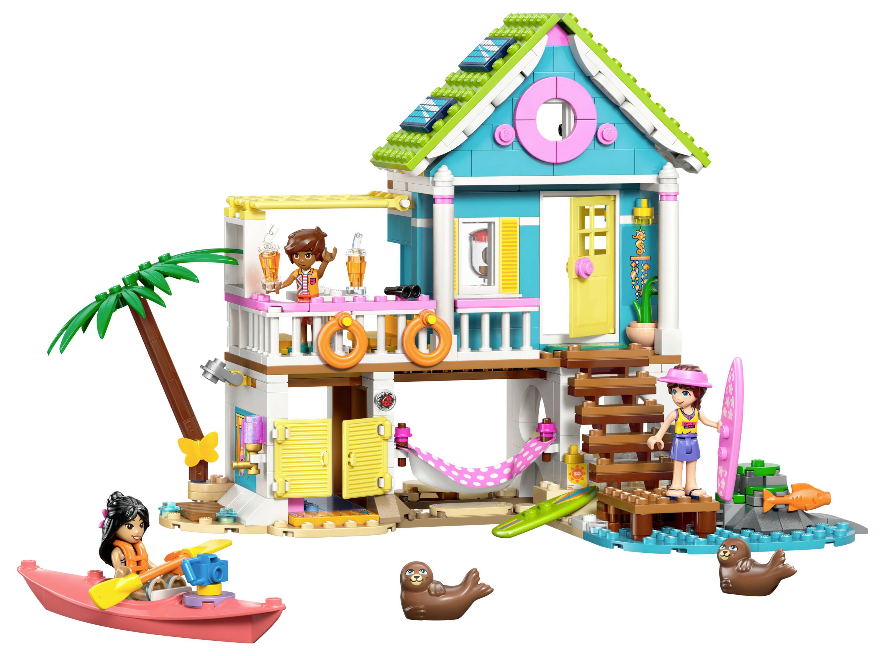 Spielhaus-Set mit buntem zweistöckigem Design, Palme und Kajak. Enthält kleine Figuren, Surfbretter und verspielt wirkende Tiere.
