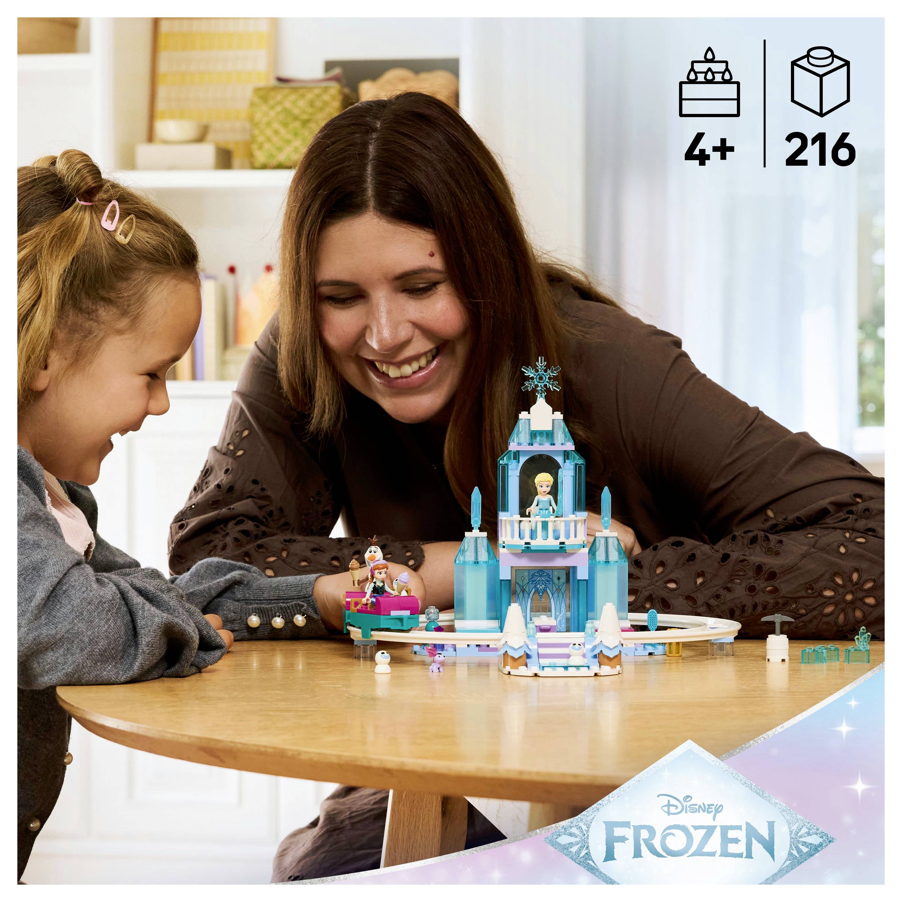 Ein Kind und ein Erwachsener lächeln und spielen mit einem blauen LEGO-Schlossset auf einem Tisch. Die Verpackung zeigt die Altersempfehlung '4+' und '216' Teile.