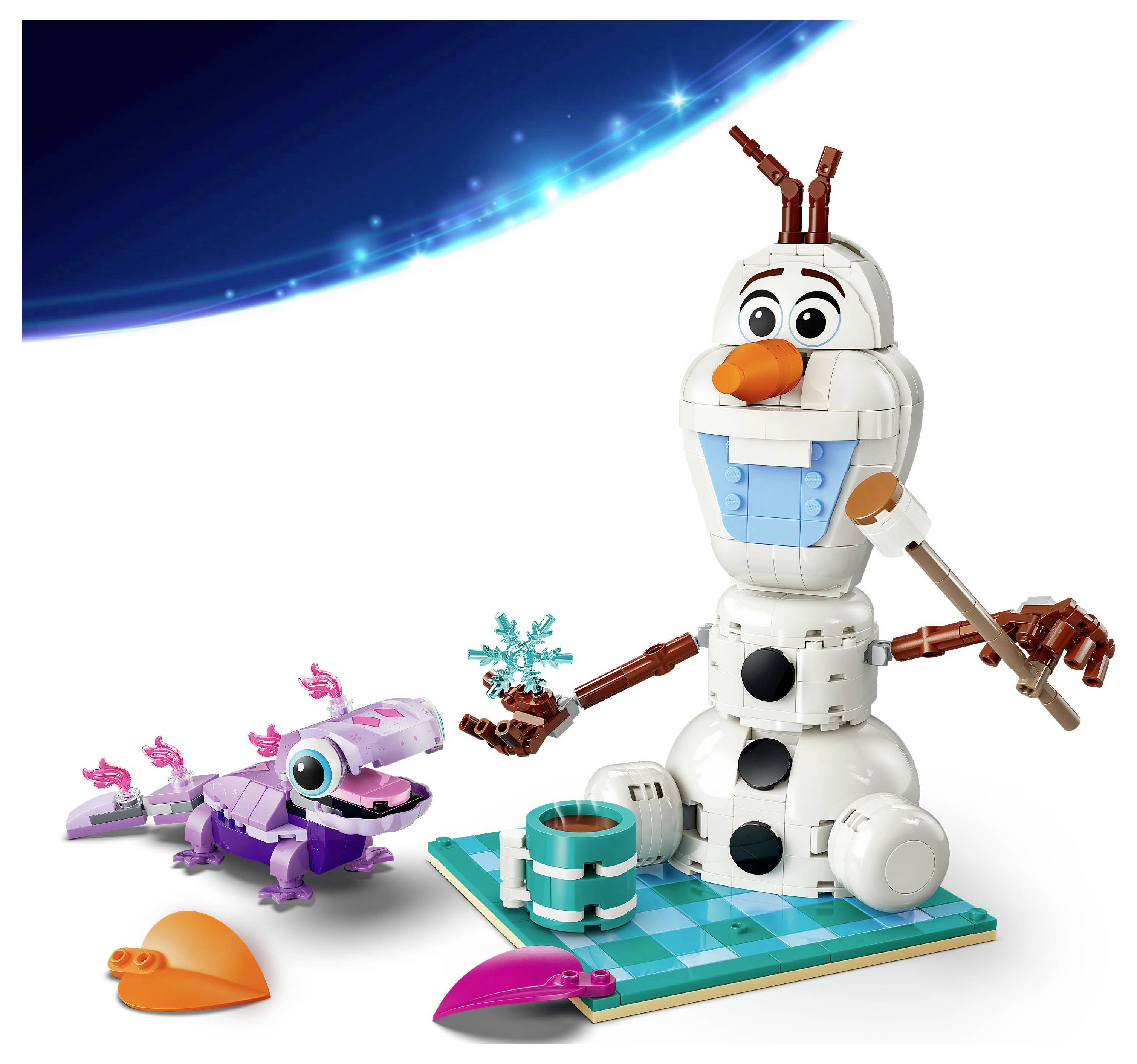 Eine LEGO-Schneefigur, die einen Pinsel und ein blaues herzförmiges Teil hält, sitzt auf einer grünen Basis, in der Nähe einer lila Eidechse.