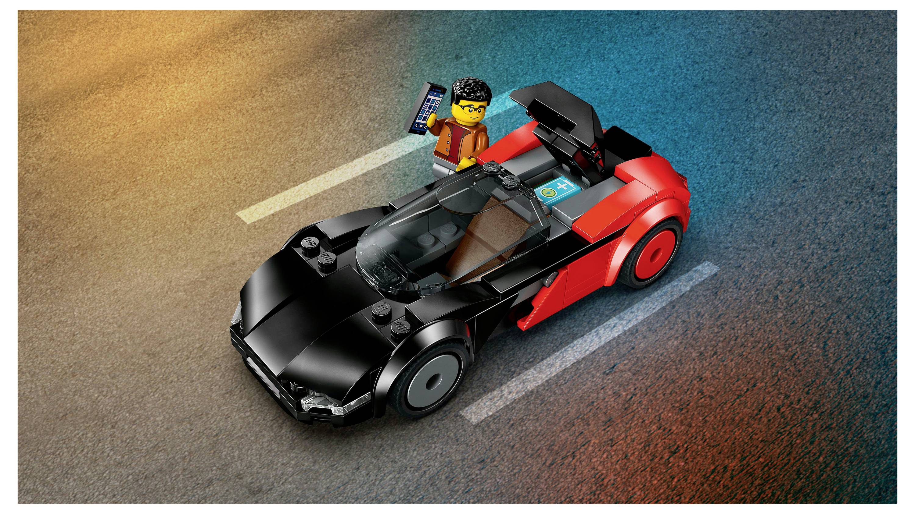 Eine LEGO-Figur steht auf einer Straße neben einem schwarzen und roten LEGO-Sportwagen und hält ein Tablet.