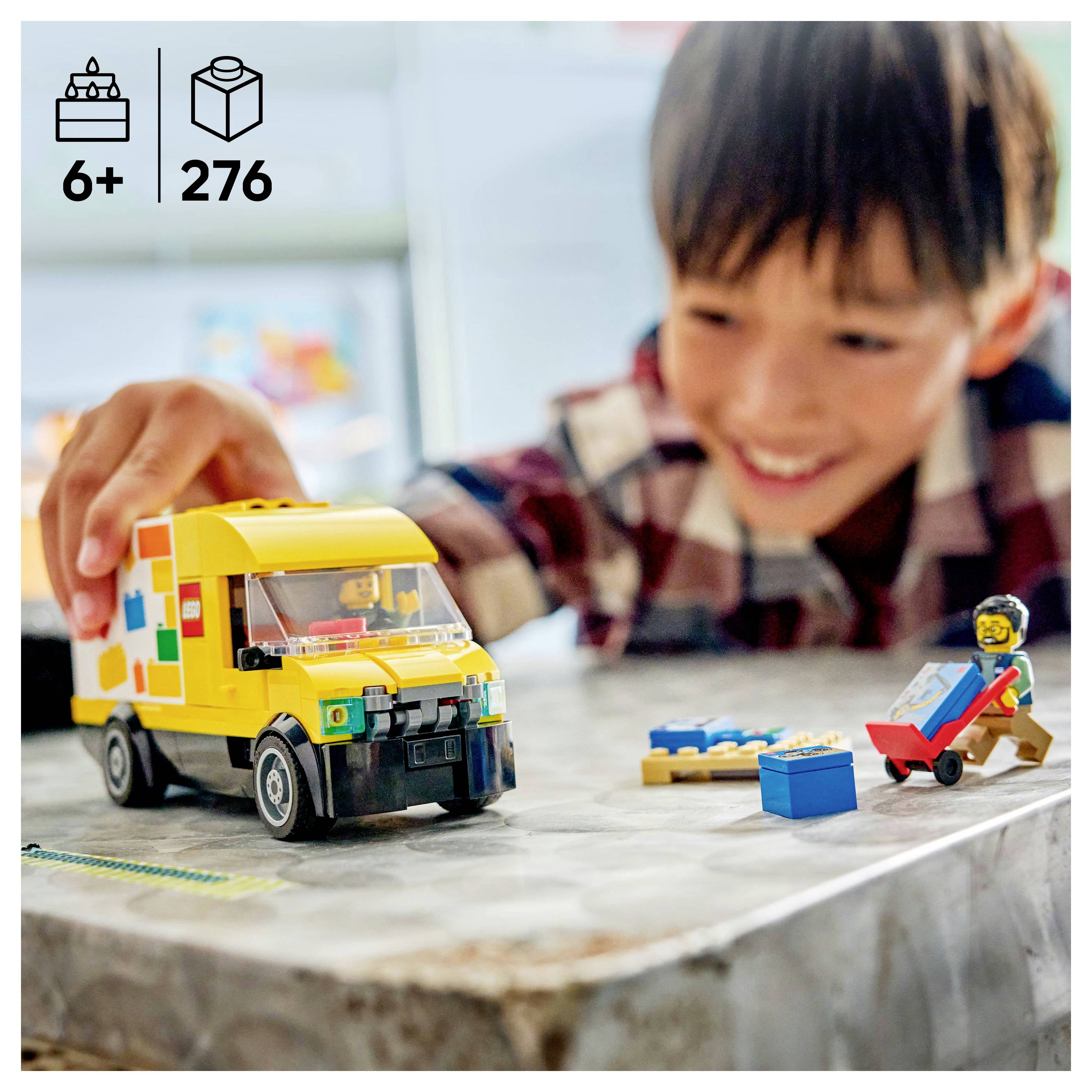 Ein Kind spielt mit einem gelben Spielzeug-Lastwagen und Bauklötzen und lächelt. Set enthält 276 Teile, für Kinder ab 6 Jahren.