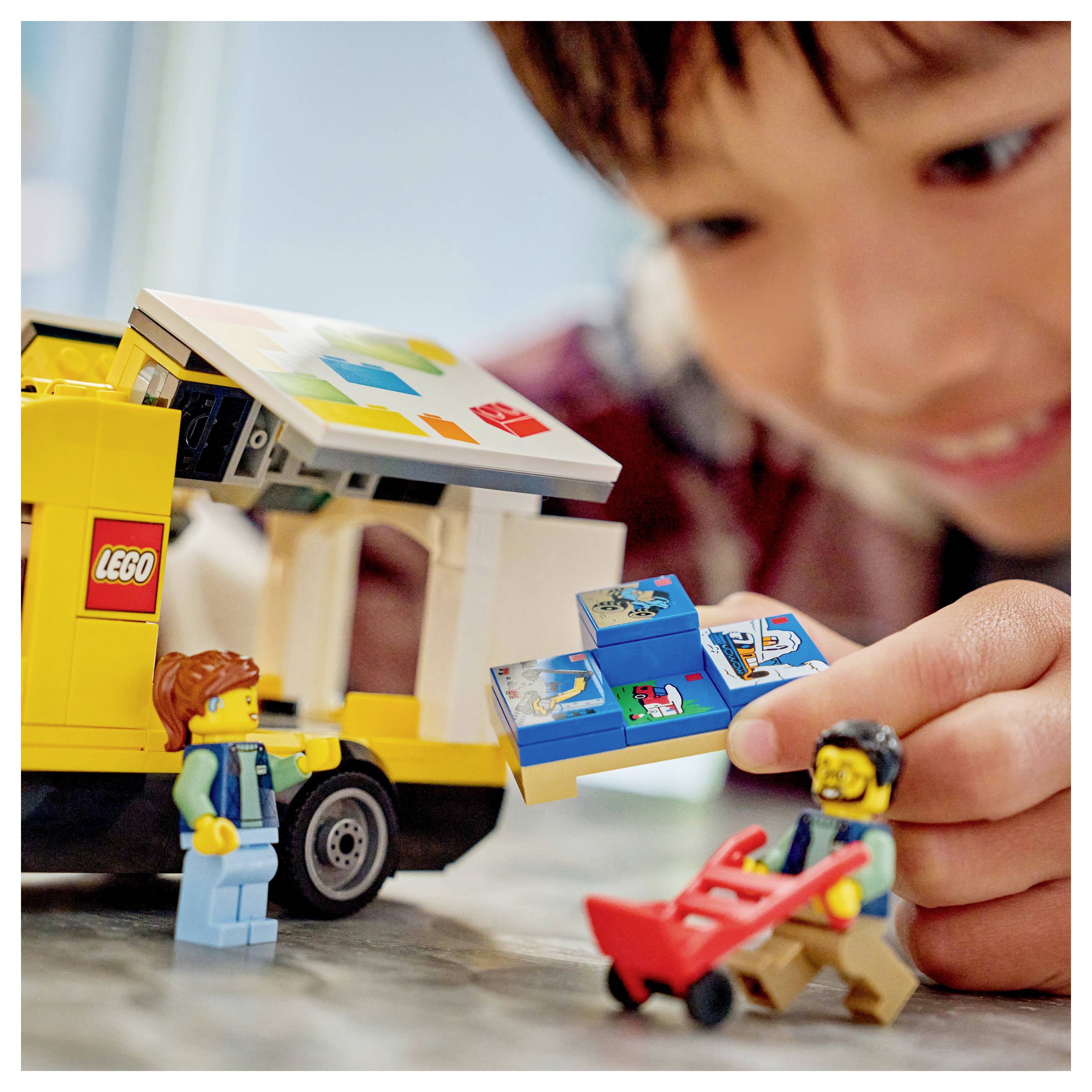 Ein Kind spielt mit einem Spielzeug-Lieferwagen und Figuren und betreibt dabei kreatives Rollenspiel, das Kreativität und Erforschung veranschaulicht.