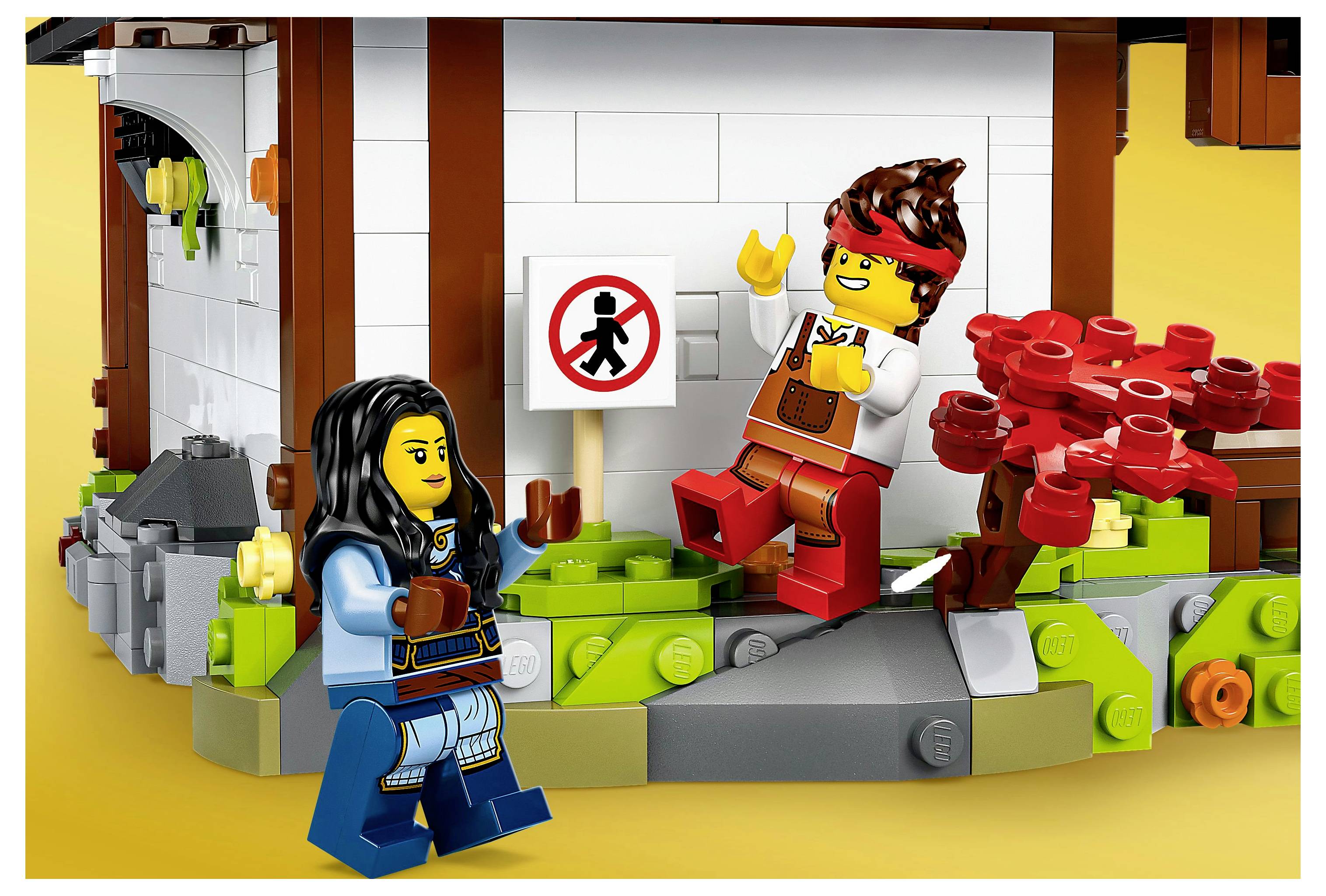 Zwei Spielzeugfiguren interagieren vor einem Gebäude. Eine Figur zeigt auf ein Schild mit einem durchgestrichenen Gehsymbol.