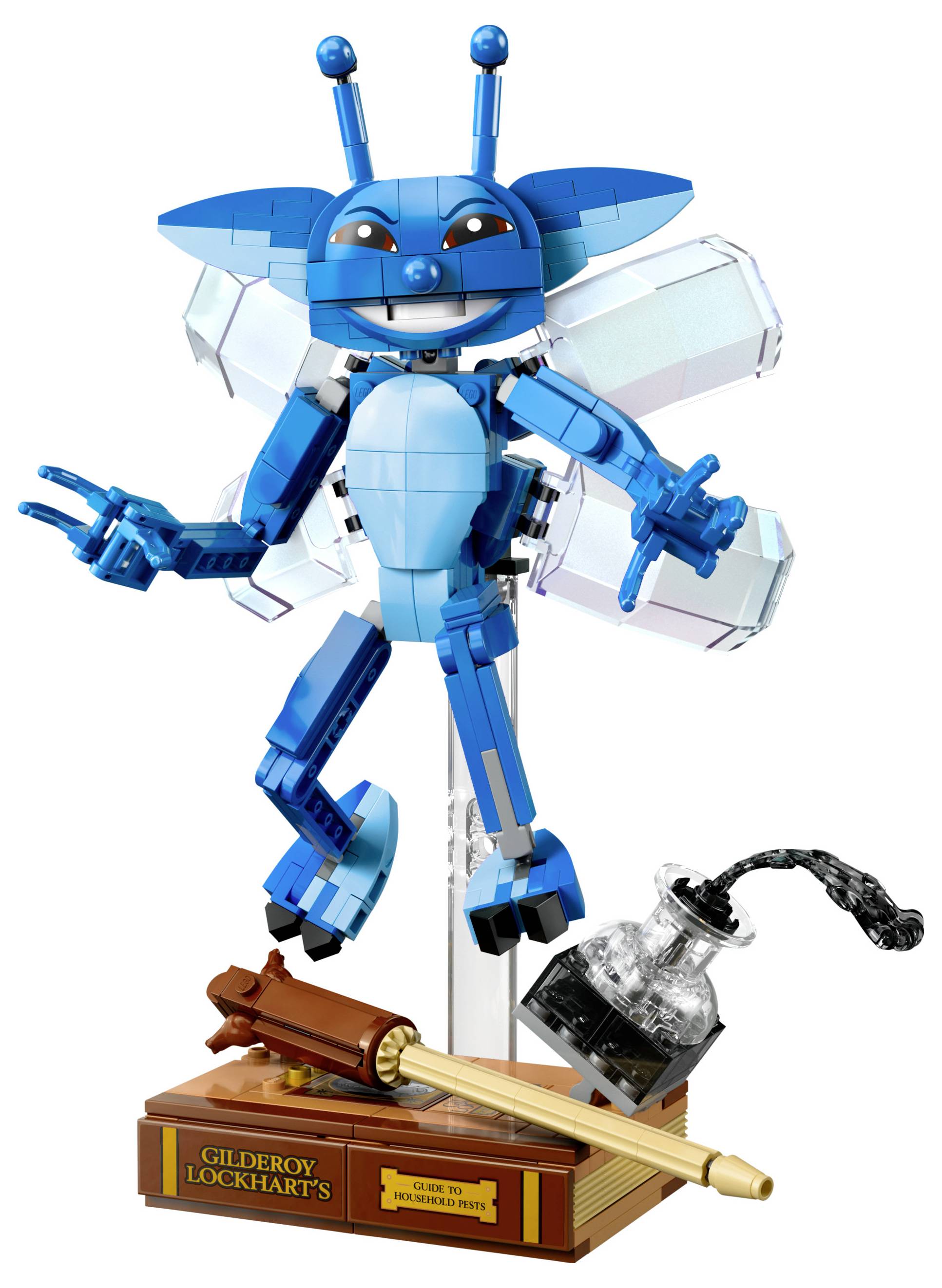 Eine blaue LEGO-Pixie-Figur mit Flügeln und Antennen posiert auf einem durchsichtigen Ständer neben einer LEGO-Tintenflasche und einer Feder auf einer braunen Basis mit der Aufschrift 