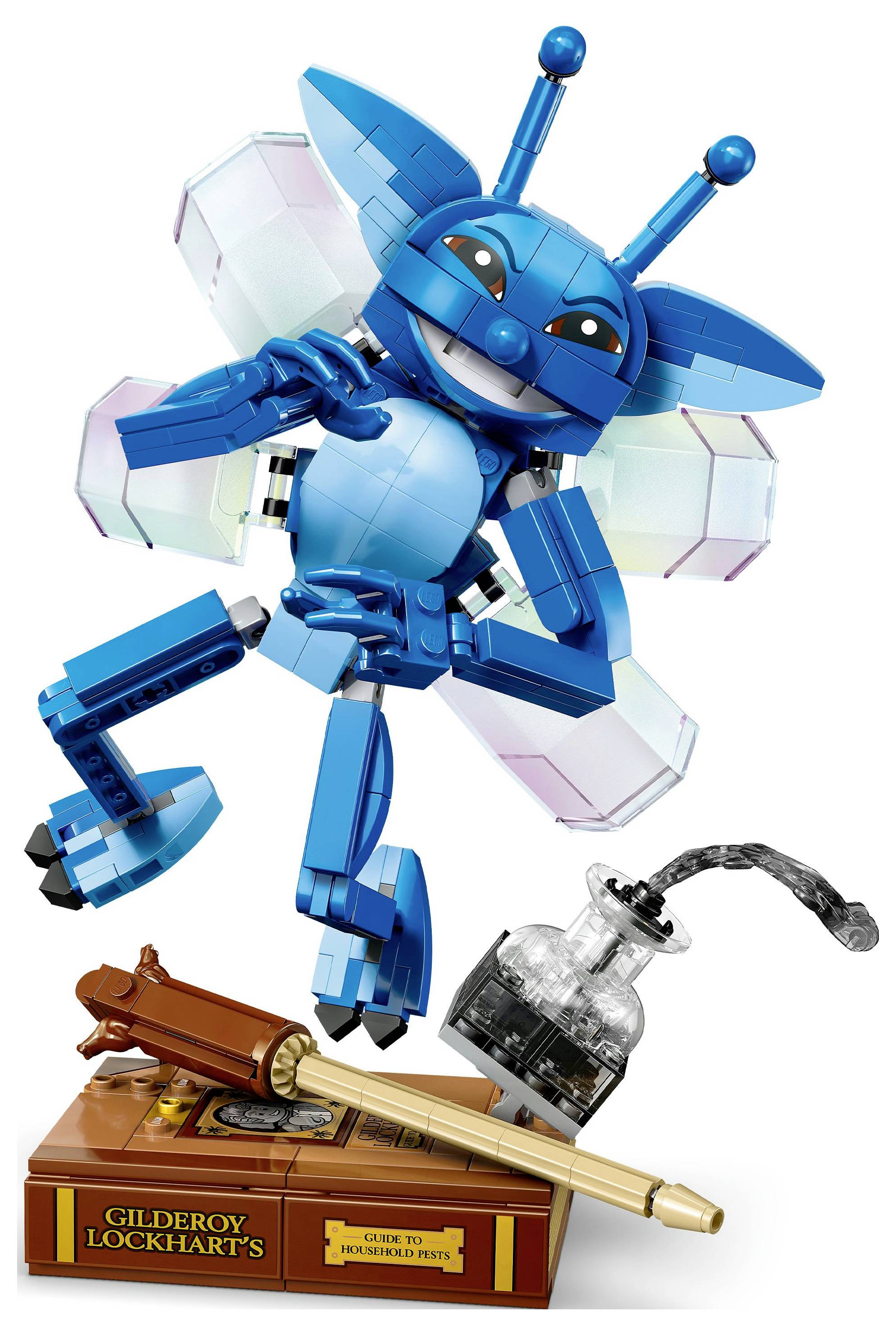 Eine blaue LEGO-Kreatur mit Flügeln posiert fröhlich über einem Ständer. Der Ständer enthält eine Feder, eine Tintenflasche und eine Plakette mit der Aufschrift 