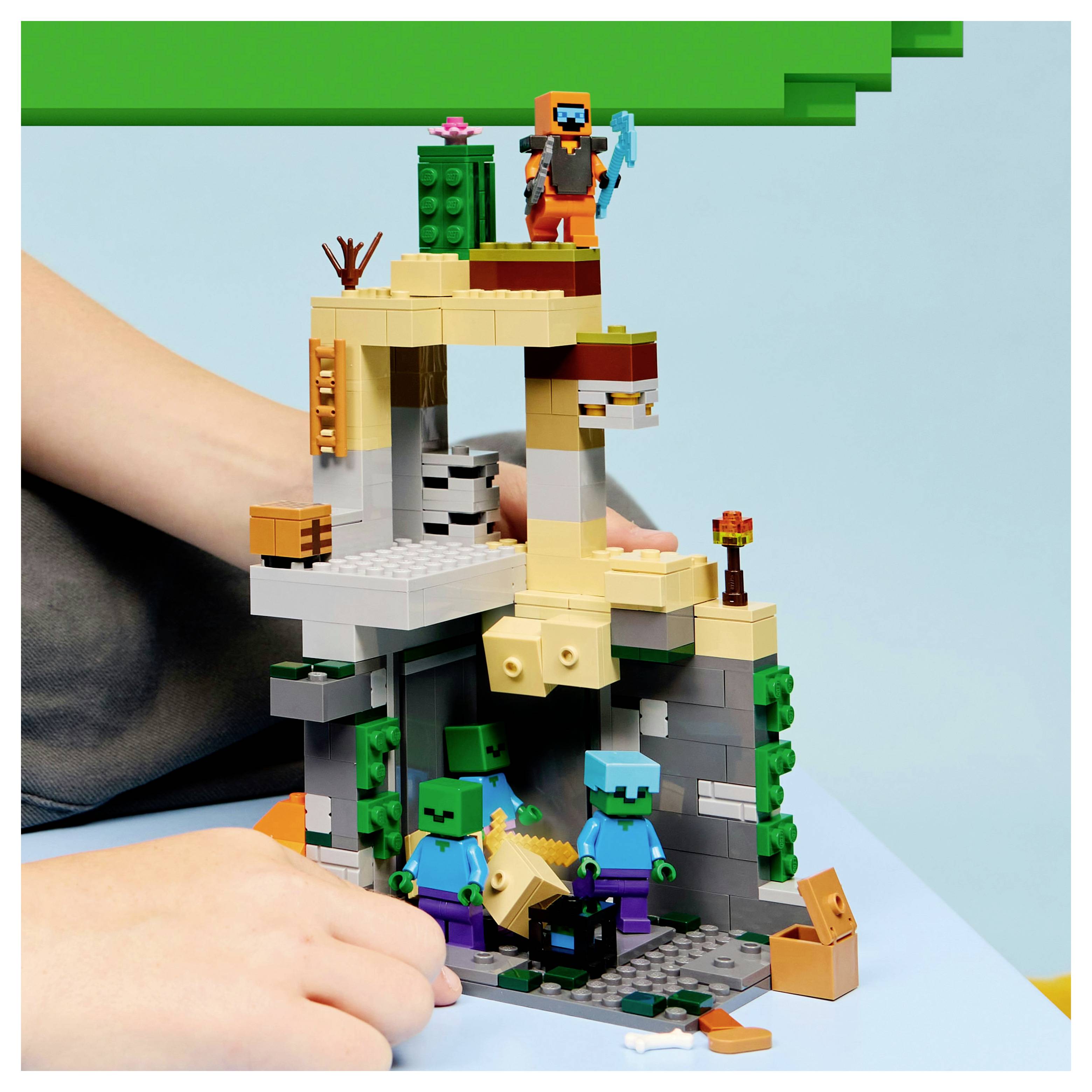 Ein Kind baut eine Szene mit Spielsteinen, die eine Figur zeigt, die ein Werkzeug auf einer Struktur hält, während zwei eckige Figuren darunter stehen.