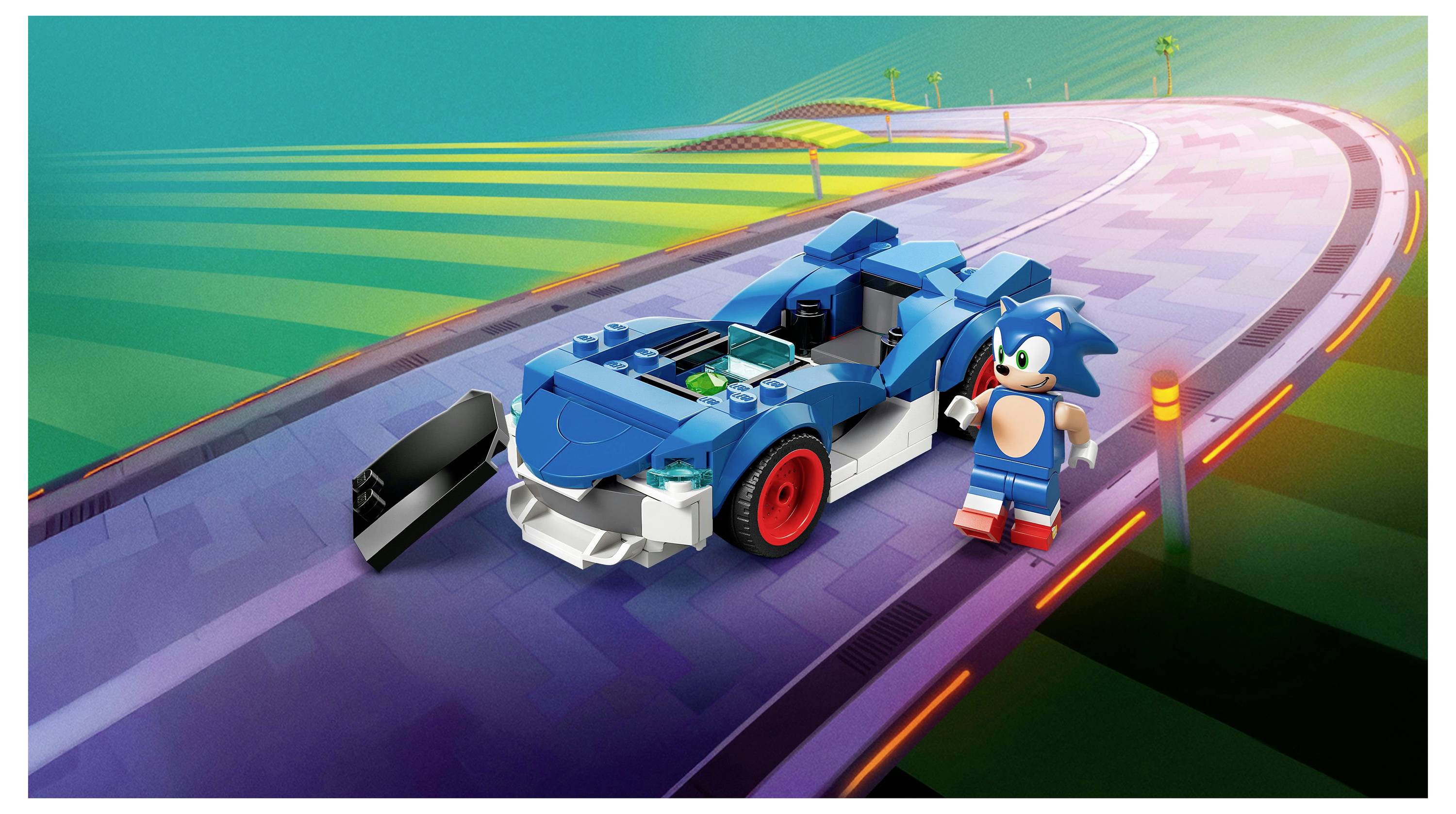 Ein blaues Spielzeugauto mit roten Rädern und eine Figur, die einem blauen Igel ähnelt, stehen auf einer bunten, geschwungenen Bahn in einer lebhaften Umgebung.