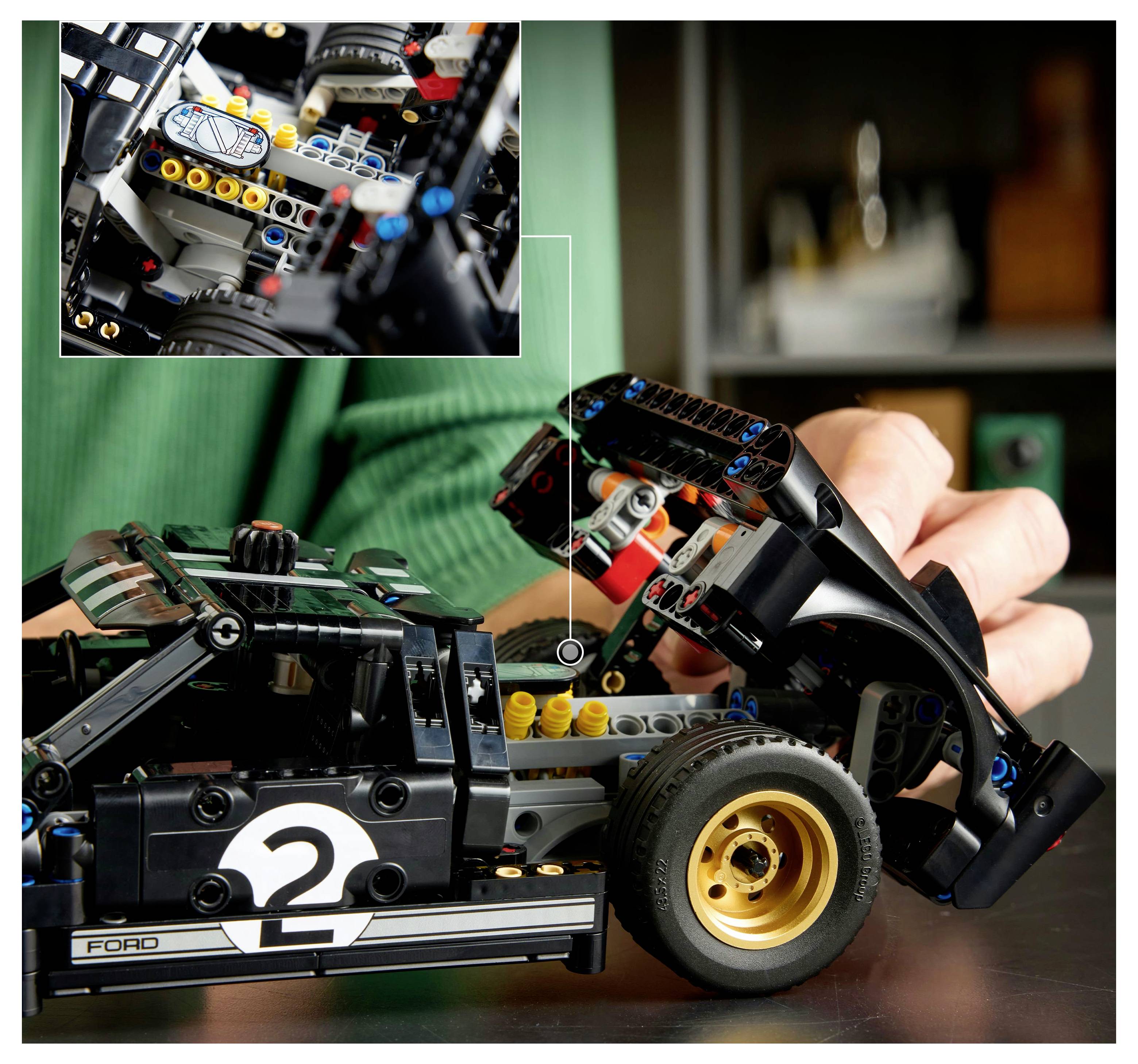 Eine Person baut ein detailliertes Modellauto mit sichtbarem Motor und Rädern. Eine Einblendung zeigt eine Nahaufnahme der Mechanik des Autos.