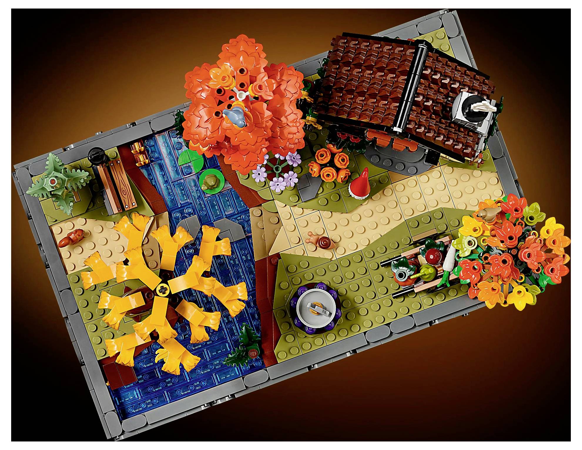 Lego-Landschaftsmodell mit Herbstbäumen, einem Bach, einem Pfad und einem kleinen Ziegelhaus, auf einer braunen Grundplatte für eine Herbstszene.