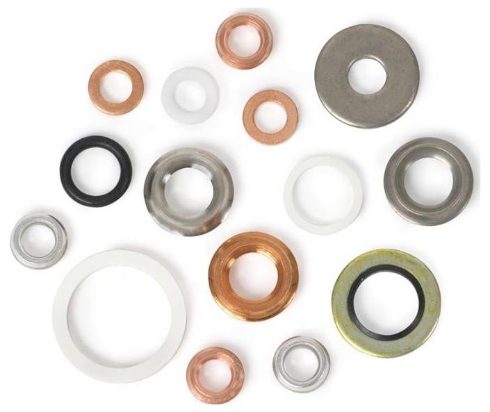 Verschiedene Unterlegscheiben aus unterschiedlichen Materialien, einschließlich Kupfer, Gummi und Stahl, in verschiedenen Größen, zufällig auf weißem Hintergrund angeordnet.