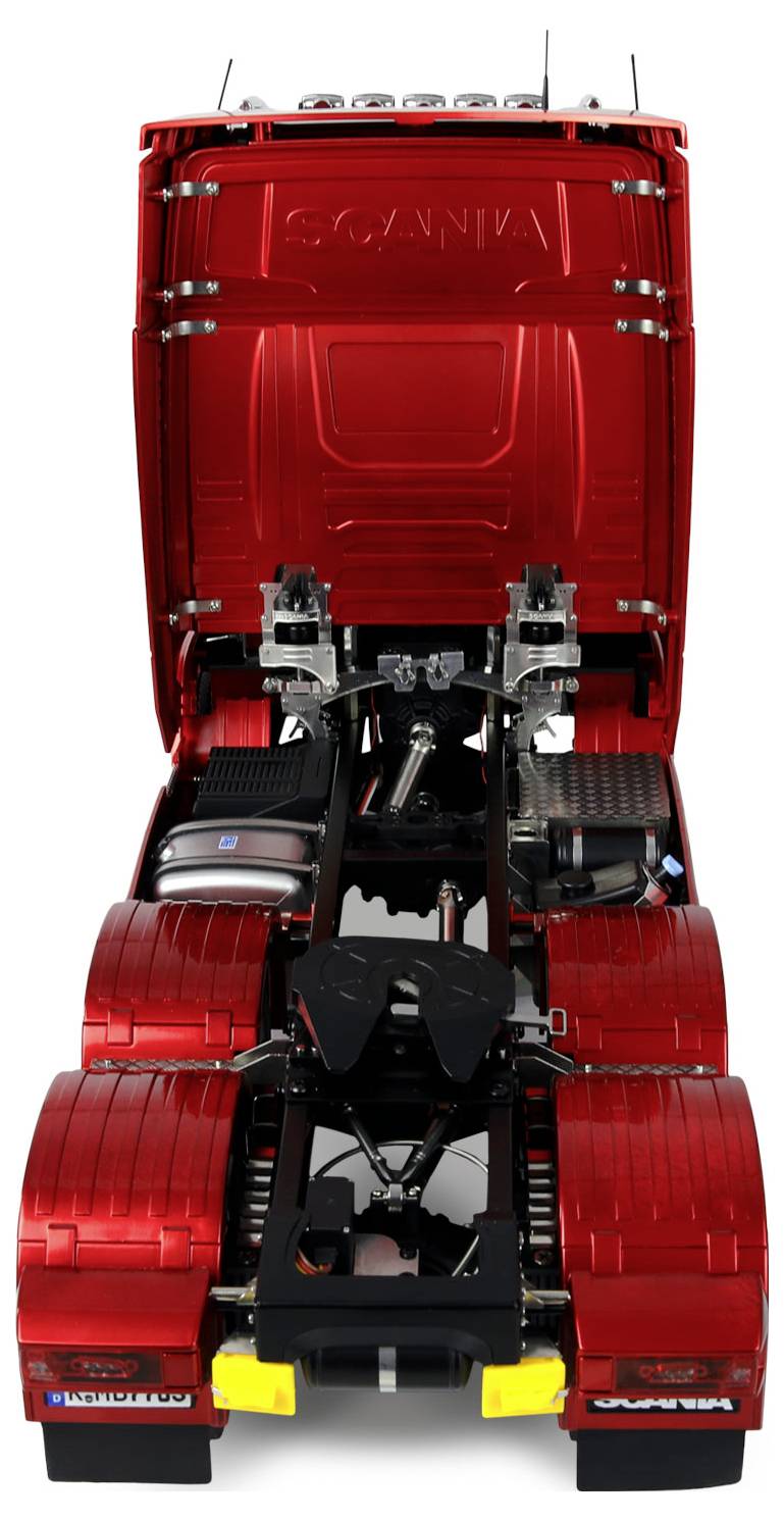 Ein roter Lastwagen, von hinten betrachtet, der sein detailliertes Fahrgestell und die offene Motorhaube zeigt und dabei die mechanischen Komponenten darunter offenlegt.