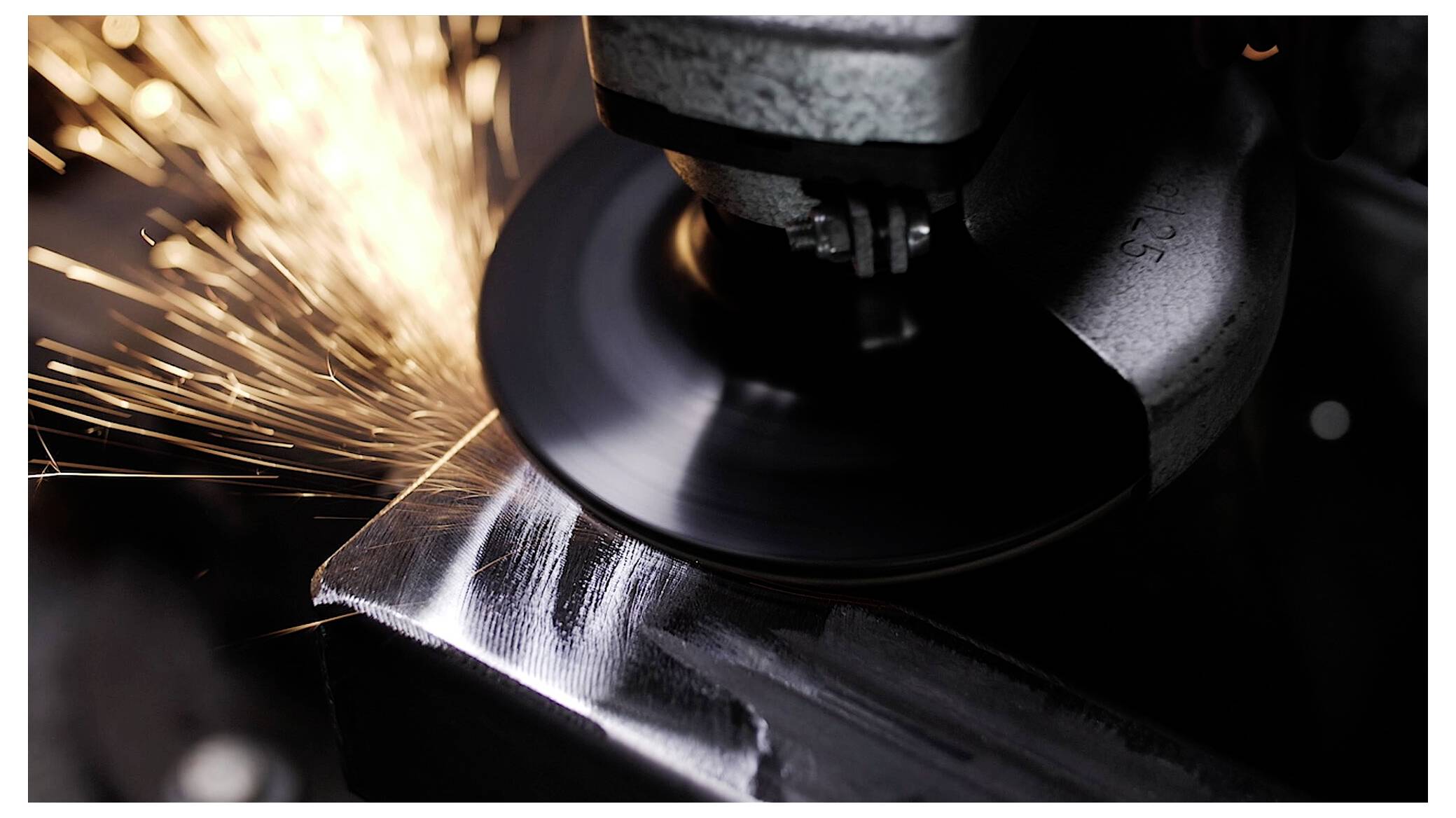 Ein Nahaufnahme einer Winkelschleifer bei Benutzung, der beim Glätten einer Metalloberfläche helle Funken ausstößt.