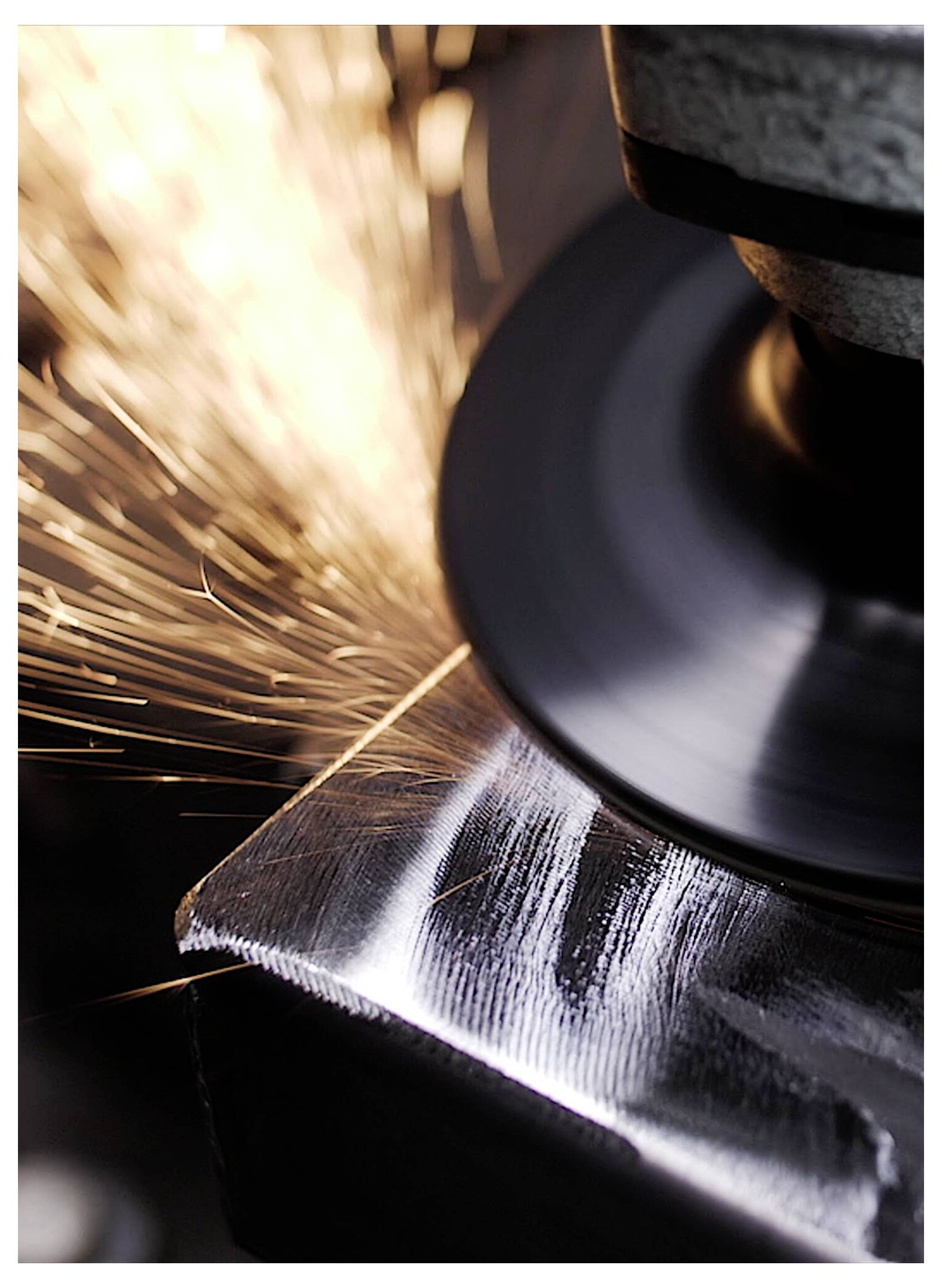 Eine Metallschleifmaschine sendet helle Funken aus, während sie ein Metallstück glättet und damit industrielle Metallbearbeitung veranschaulicht.