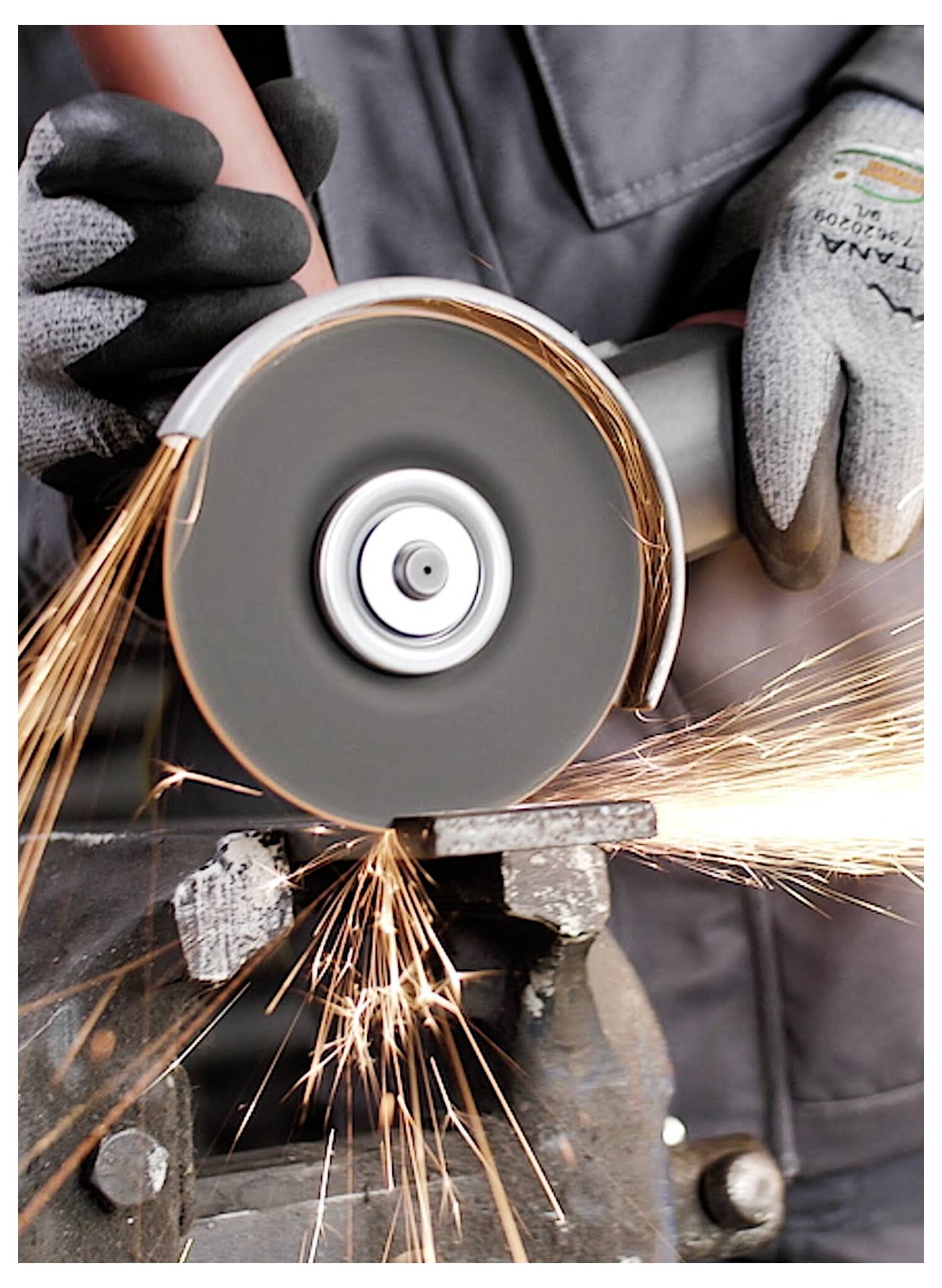 Eine Person mit Handschuhen verwendet einen Winkelschleifer an Metall, wobei Funken entstehen.