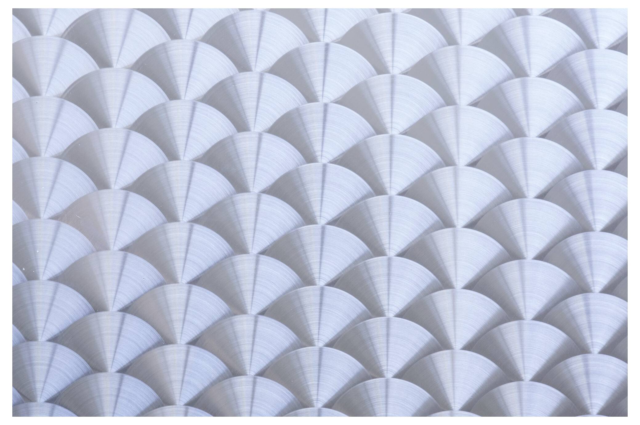 Das Bild zeigt ein Muster überlappender metallischer Fächerformen, die eine geometrische, strukturierte Oberfläche erzeugen.