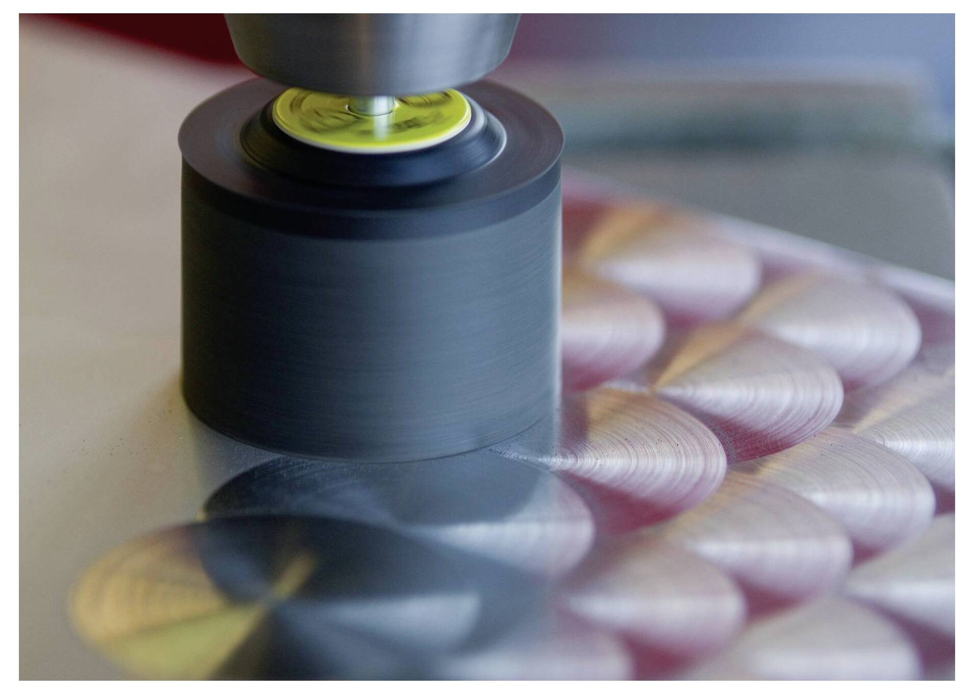 Eine Metallpoliermaschine glättet eine Metalloberfläche und erzeugt dabei kreisförmige Muster. Der Vorgang unterstreicht Präzision und industrielle Veredelung.