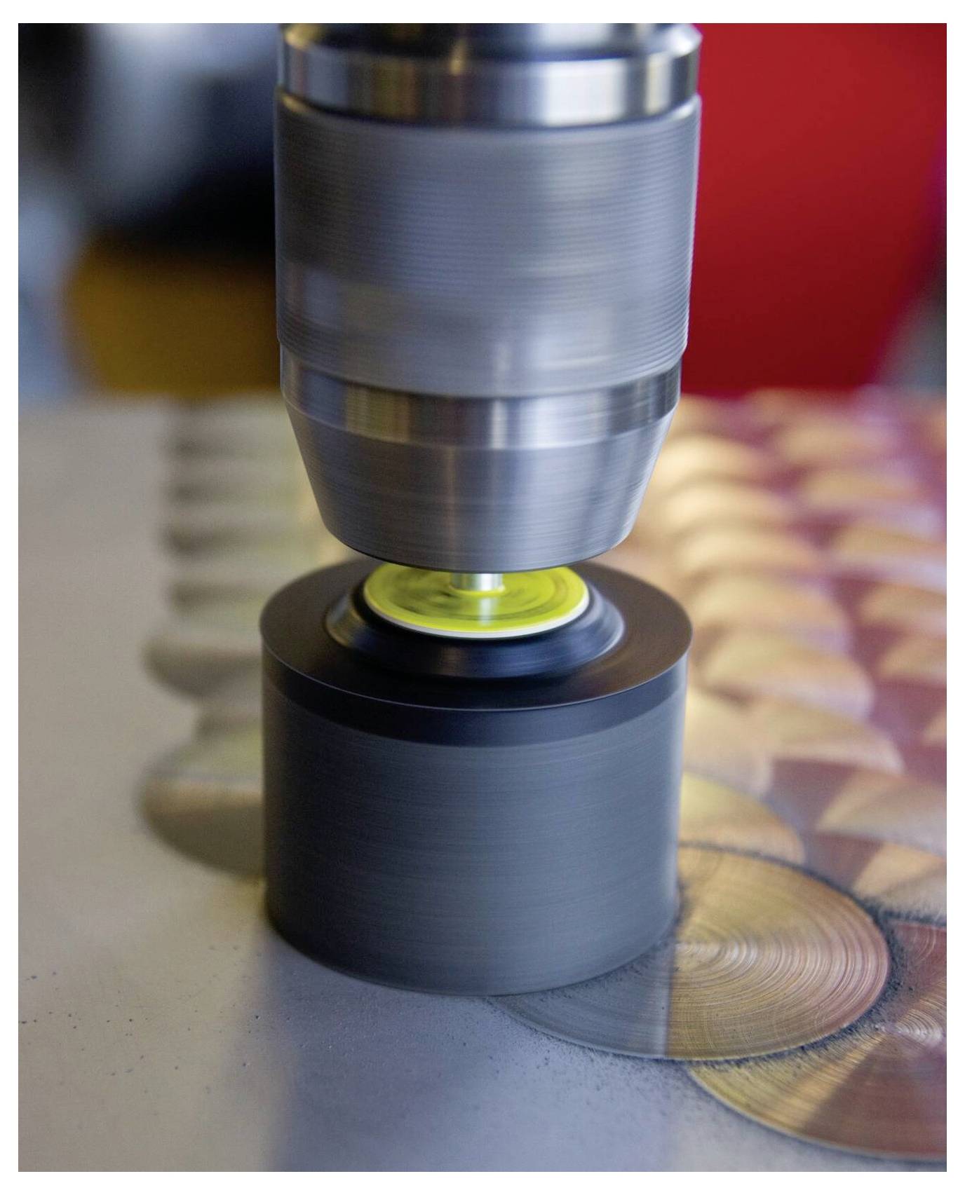 Eine Nahaufnahme einer Maschine, die eine metallische Oberfläche poliert und dabei kreisförmige Muster erzeugt, die in ihrer glänzenden Textur und Farbe variieren.