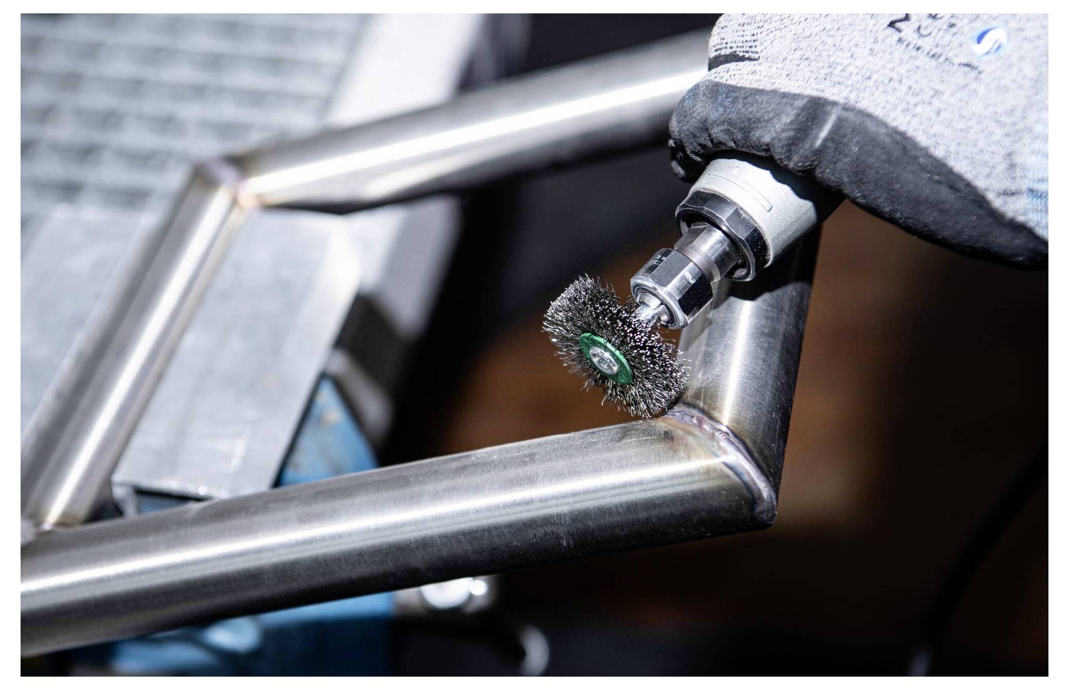 Ein Metallrahmen, der mit einem Rotationsbürstenwerk­zeug poliert wird und eine Metallbearbeitung oder Oberflächenbehandlung zeigt, wobei eine feine handwerkliche Fertigkeit hervorgehoben wird.