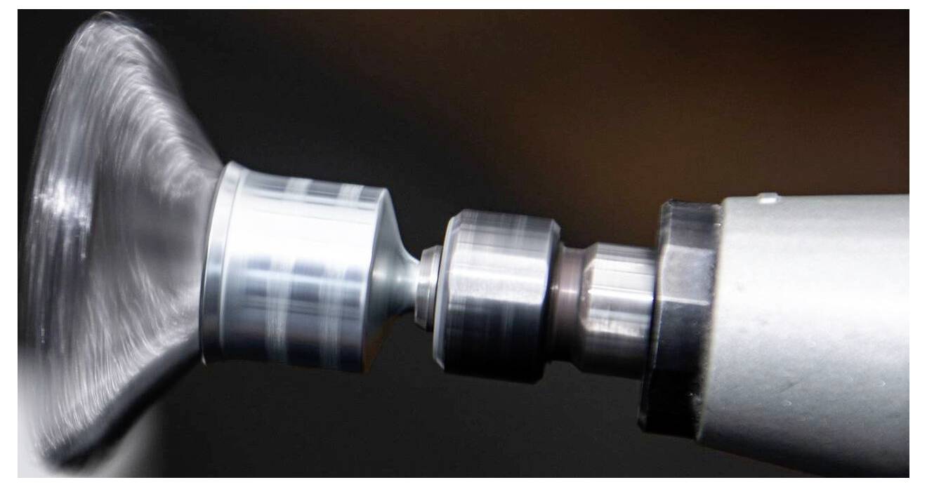 Eine Nahaufnahme eines rotierenden Metallteils an einer Maschine, die einen hochgeschwindigkeitlichen Polier- oder Bearbeitungsprozess veranschaulicht.