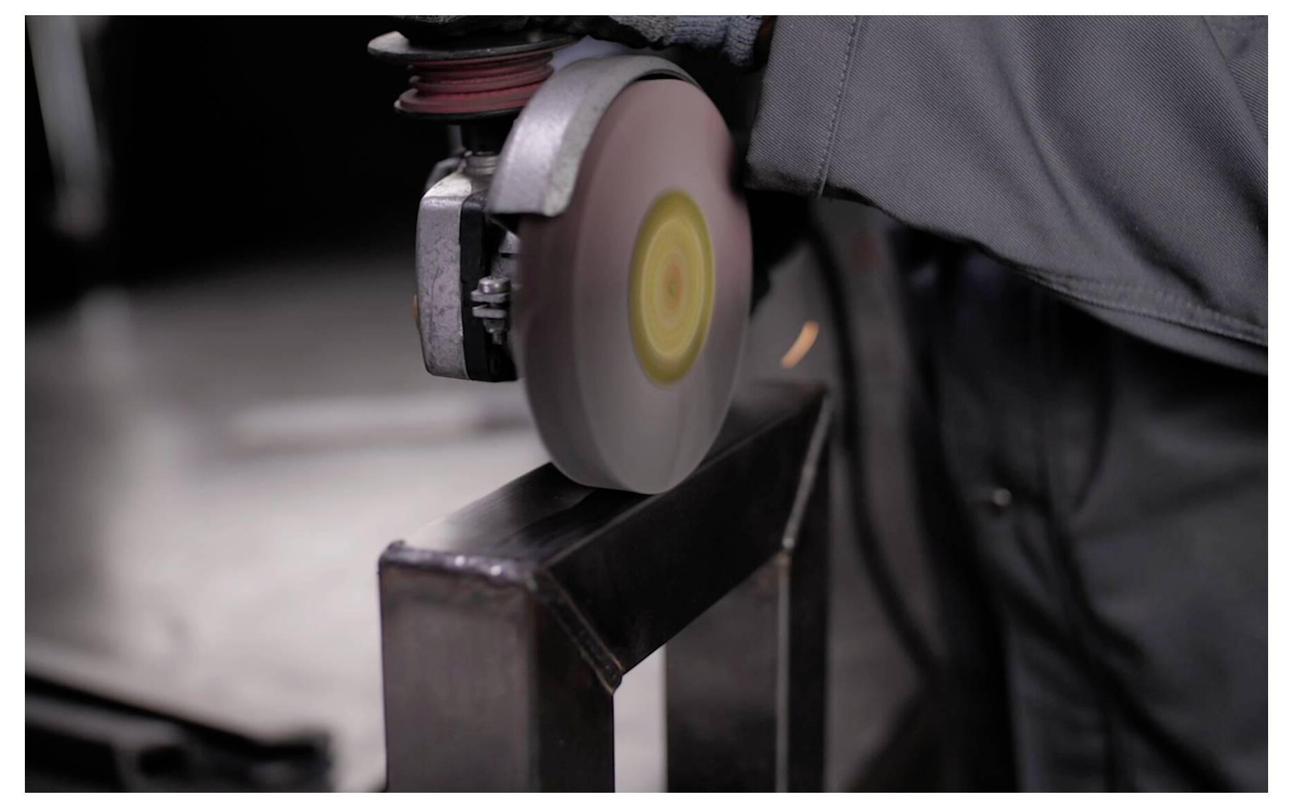 Eine Person bearbeitet Metall mit einer Winkelschleifmaschine und erzeugt Funken. Die Nahaufnahme betont das Werkzeug in Aktion und unterstreicht die Werkstattszene.