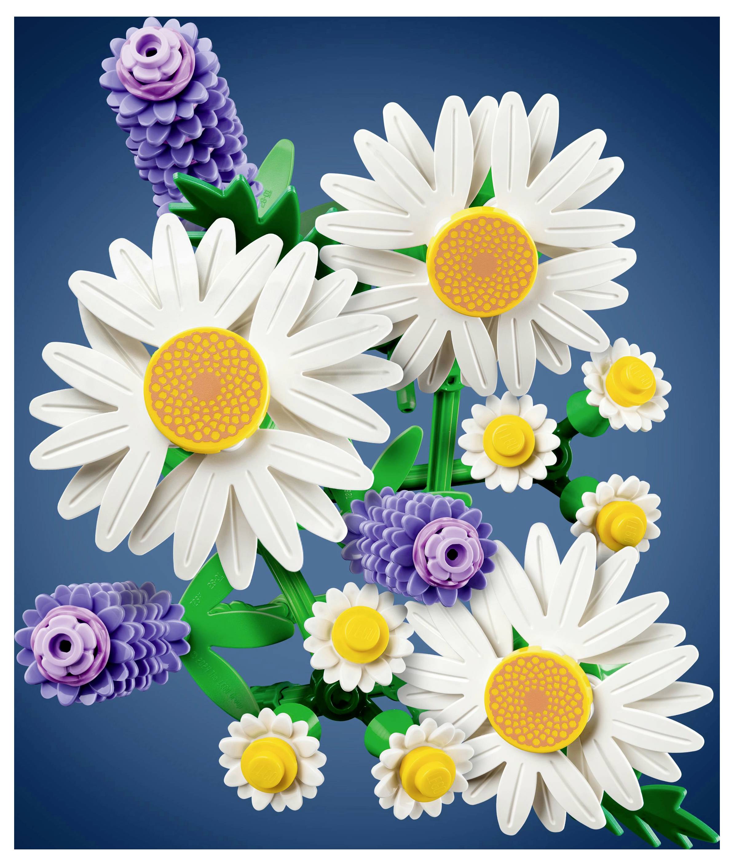 Kunststoffblumen aus ineinandergreifenden Bausteinen, mit weißen Gänseblümchen mit gelben Zentren und lila Lavendel vor einem blauen Hintergrund.