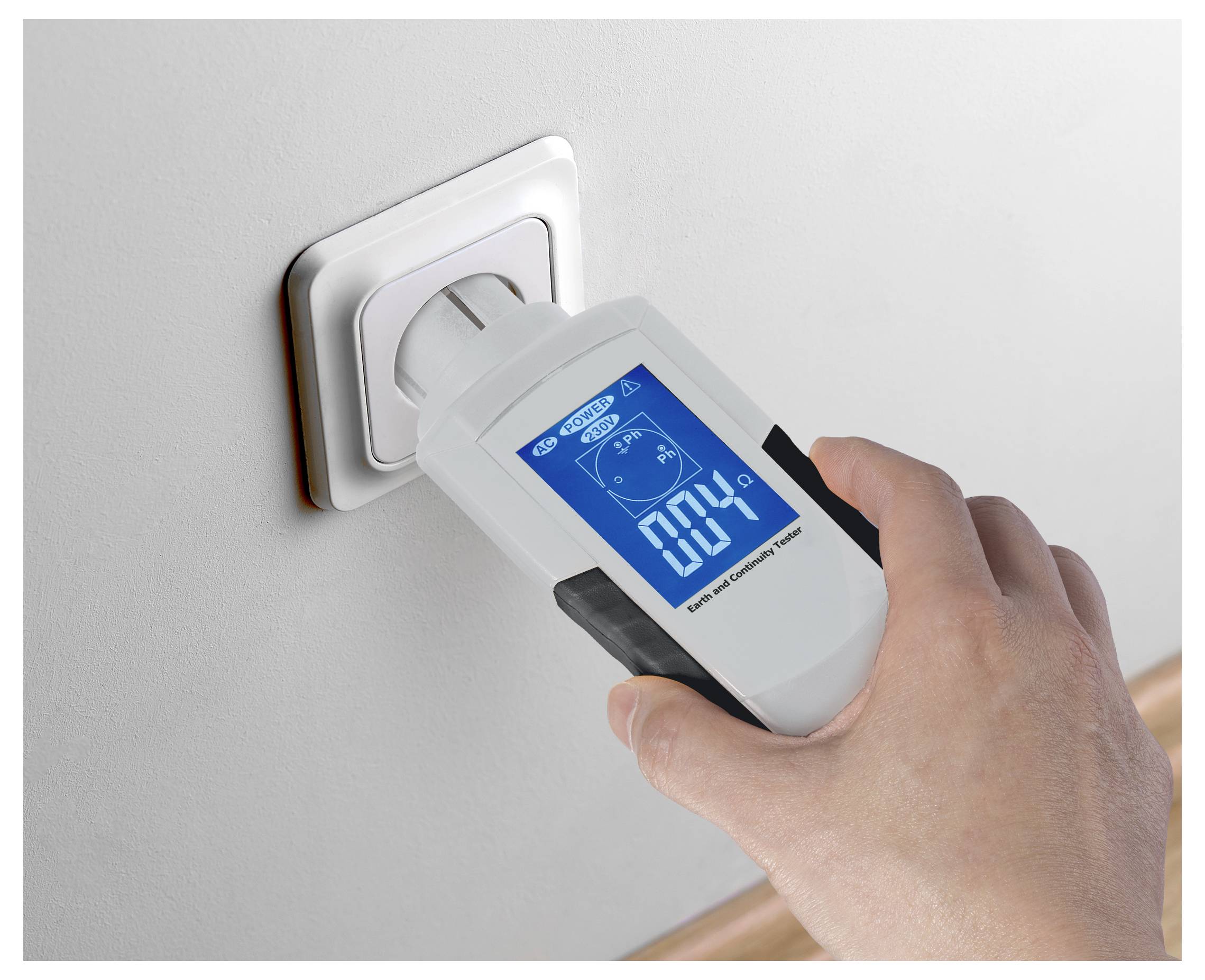 Eine Hand hält ein Energiemessgerät, das in eine Wandsteckdose eingesteckt ist und auf seinem Bildschirm „000