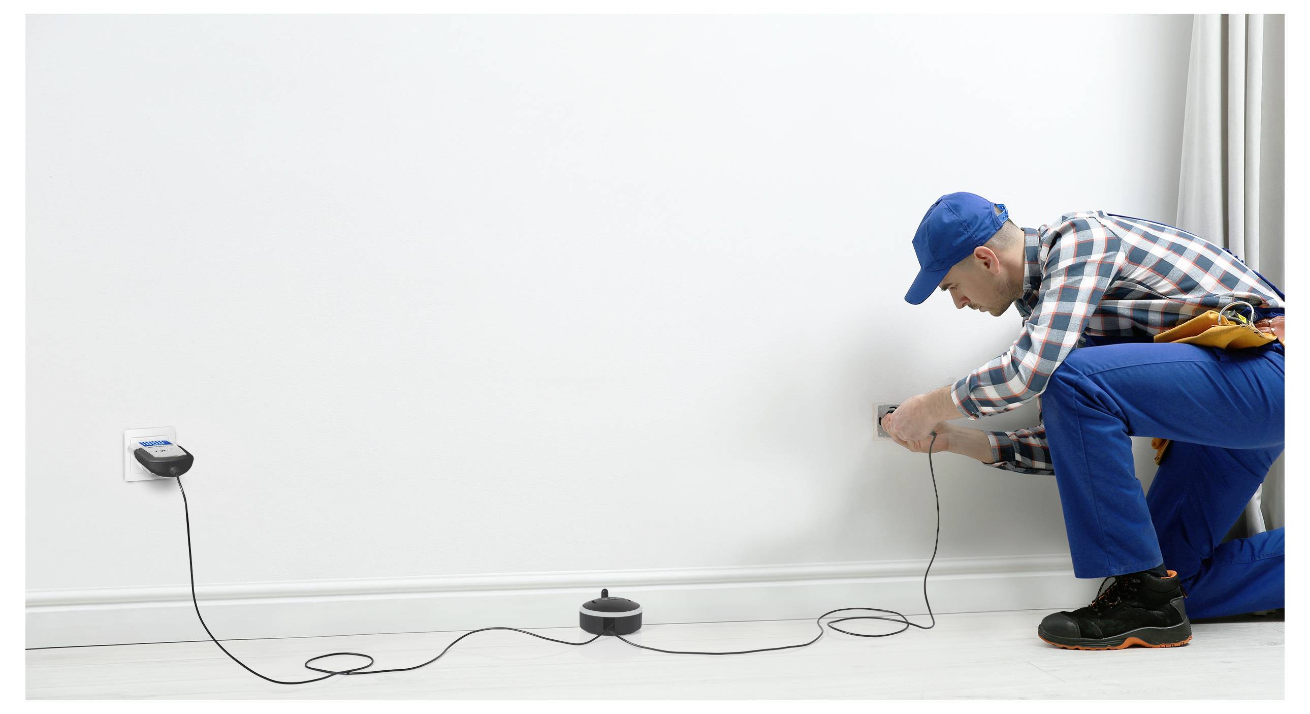 Eine Person in Arbeitskleidung, die eine Steckdose mit Ausrüstung prüft, um Sicherheit und Funktionsfähigkeit zu gewährleisten.