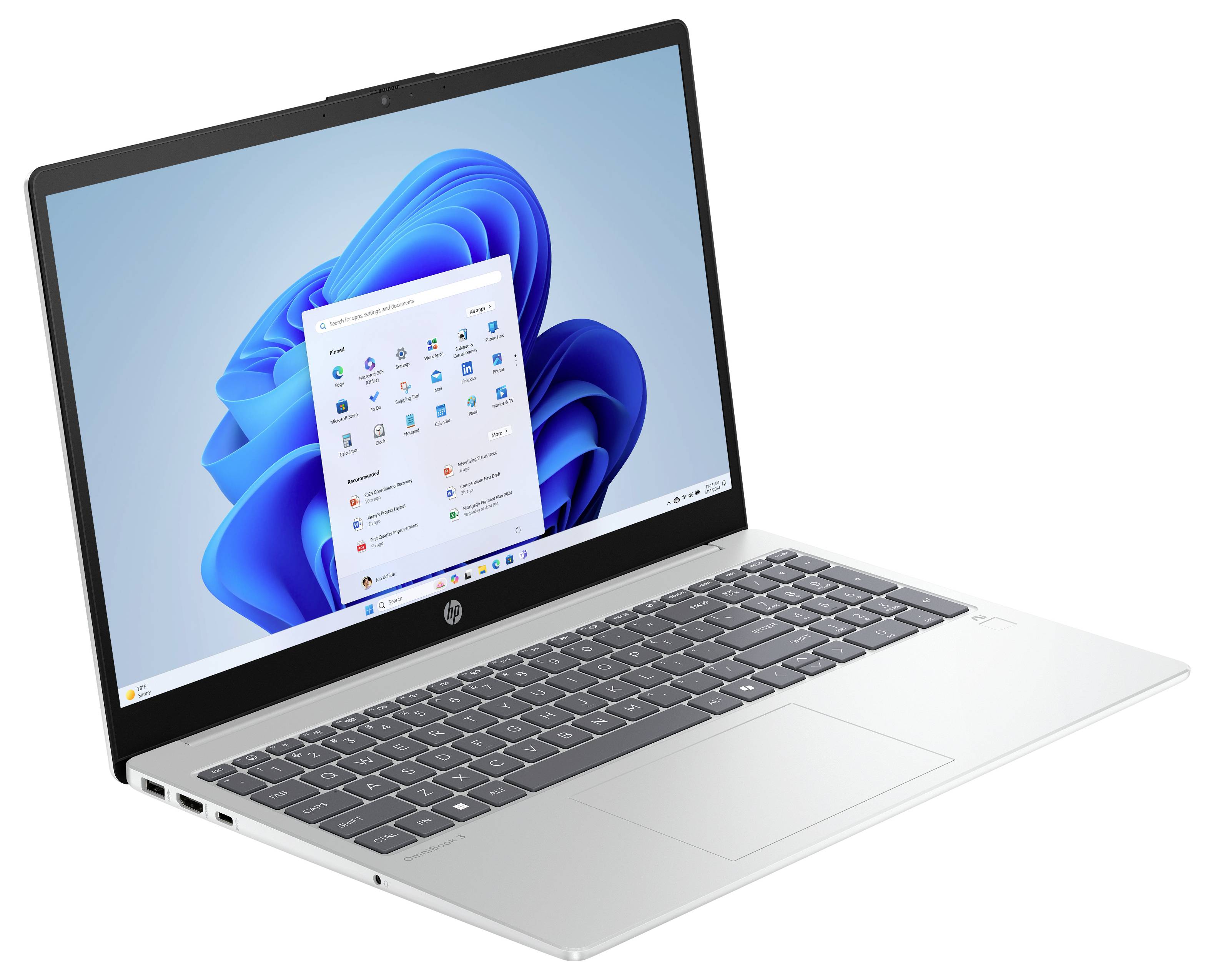 Ein Laptop, der den Windows 11 Startbildschirm mit App-Symbolen wie Mail, Edge und Word zeigt. Das Gerät hat eine silberne Oberfläche und eine schwarze Tastatur.