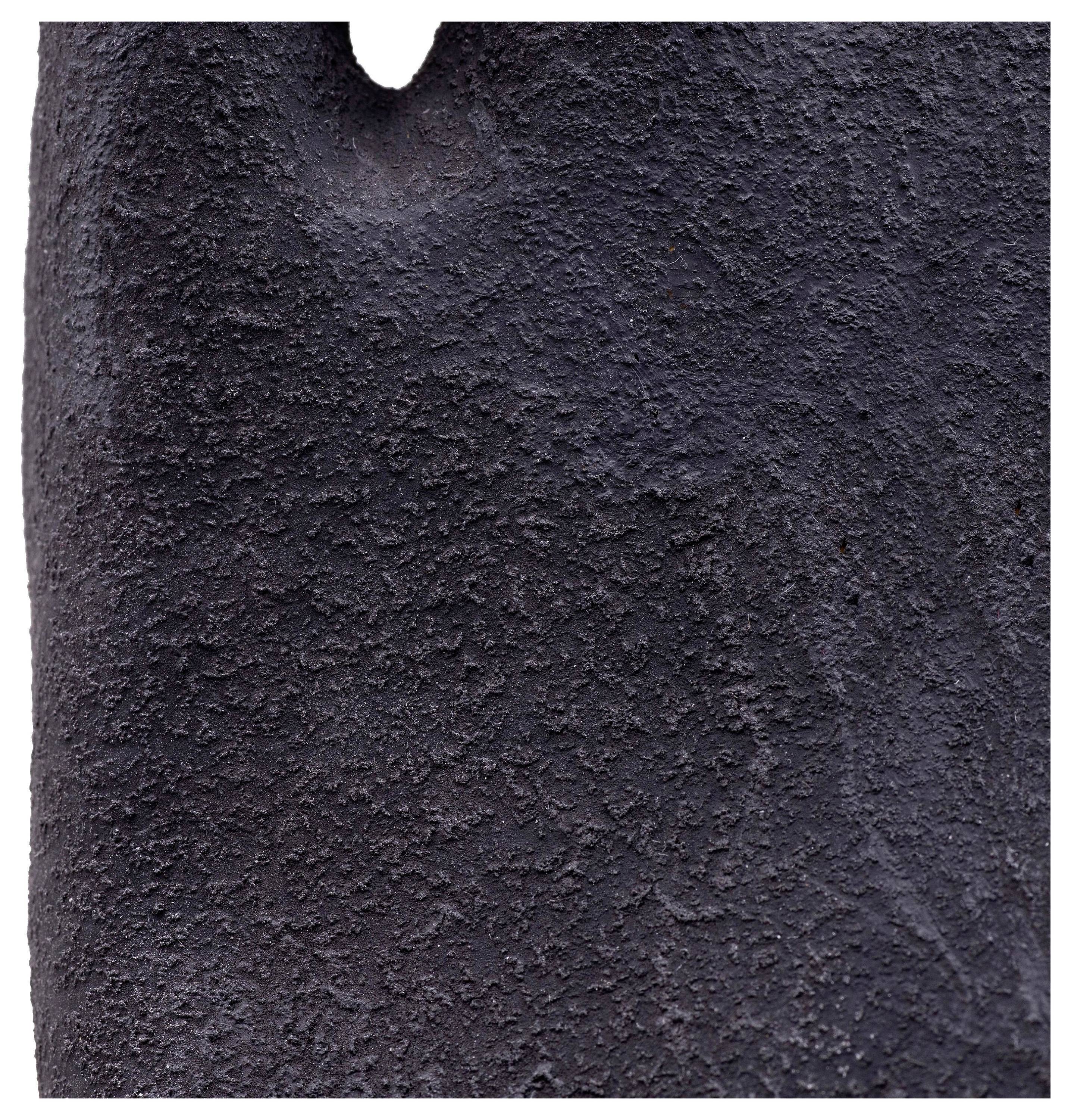 Ein Nahaufnahmebild einer dunklen, strukturierten Oberfläche, möglicherweise ähnlich einem Vulkangestein oder Asphalt, mit einer leichten Vertiefung an der Spitze.