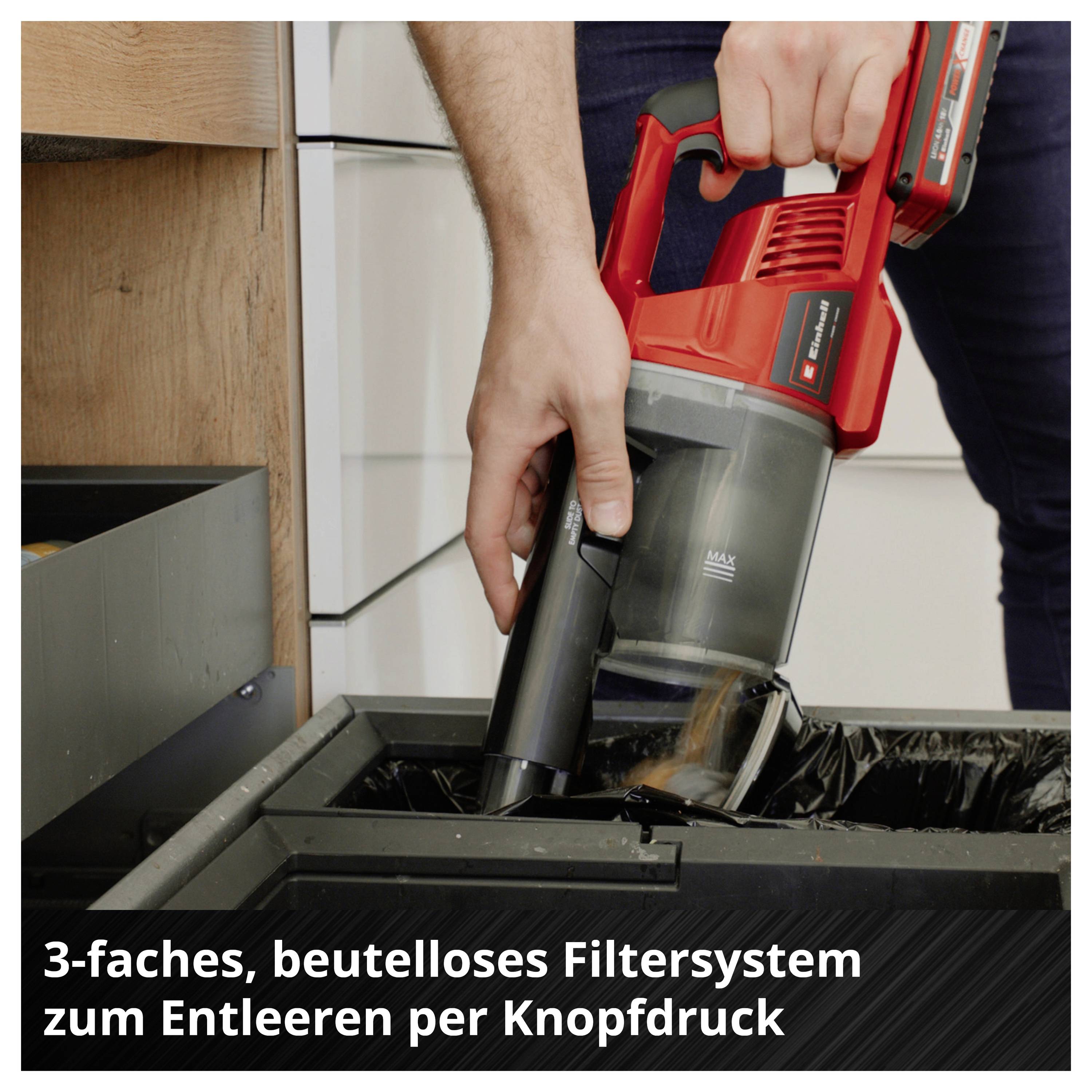 Eine Person entleert einen Staubsauger mit einem dreifachen, beutellosen Filtersystem per Knopfdruck über einem Mülleimer.
