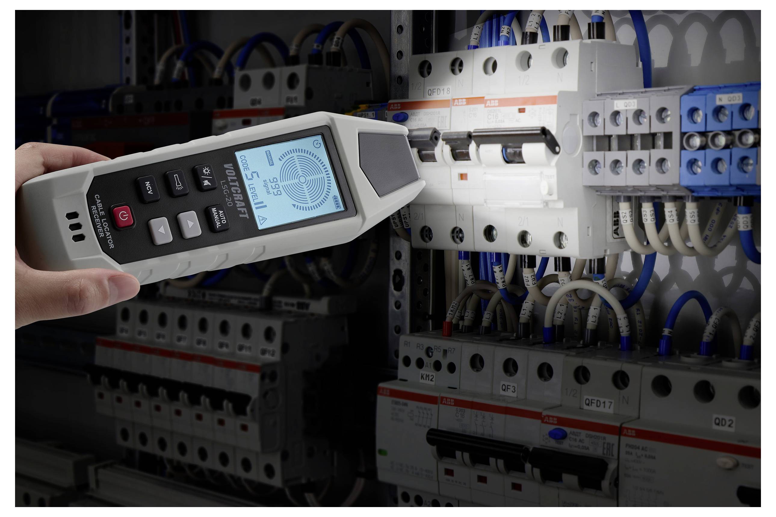 Eine Hand hält ein digitales Elektroprüfgerät neben einem Leistungsschutzschalter-Panel. Der Bildschirm des Prüfgeräts zeigt Messwerte an und gibt das Vorhandensein von Spannung an.
