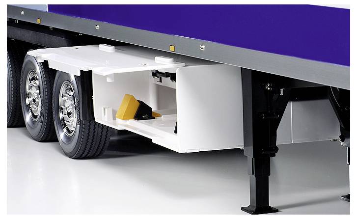 Ein Sattelanhänger mit einem weißen Laderaum, dessen Tür geöffnet ist und einen gelben Radkeil im Inneren zeigt. Der Anhänger hat glänzende Doppelreifen.