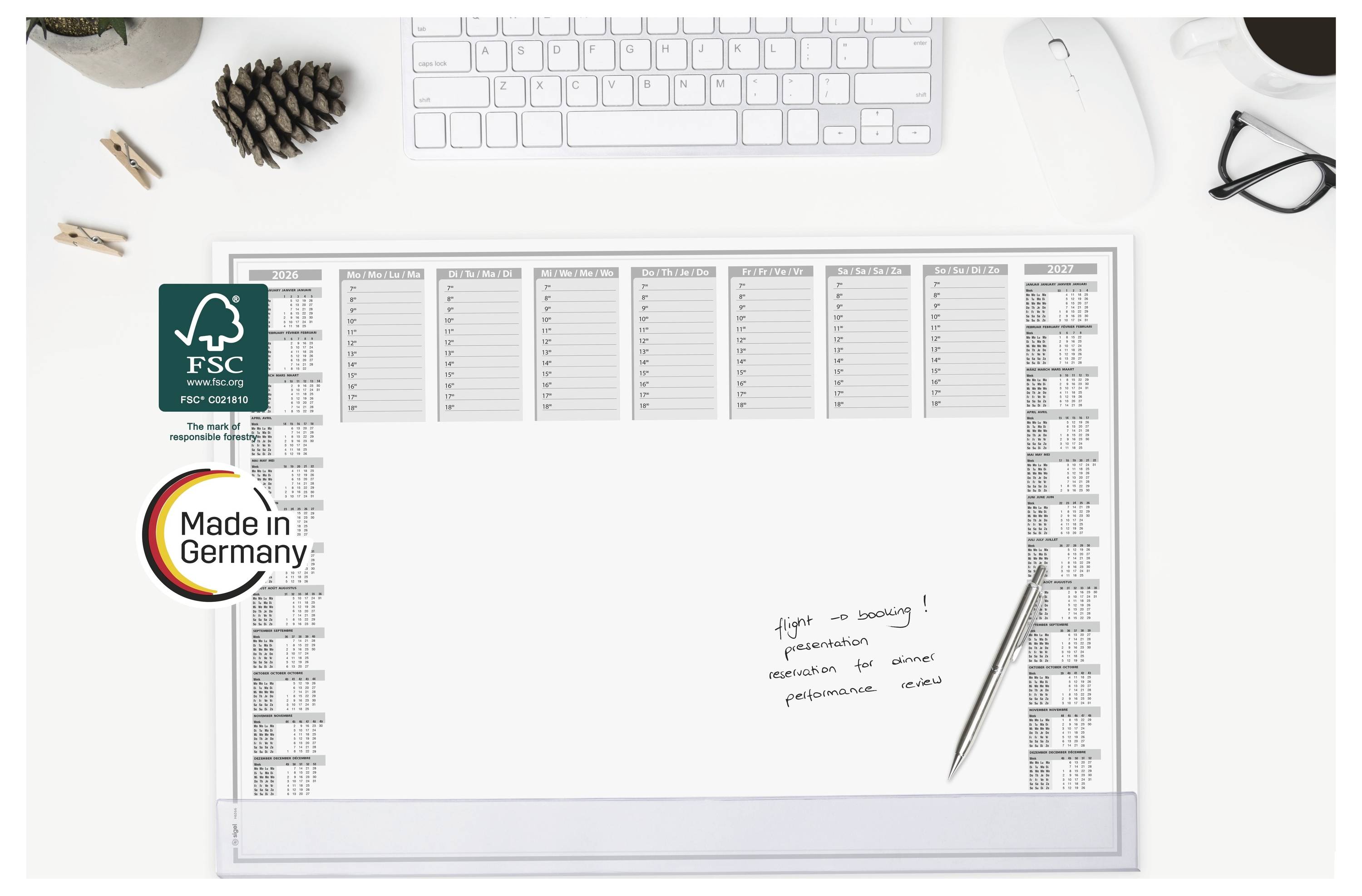 Draufsicht auf einen leeren weißen Schreibtischkalender mit FSC- und „Made in Germany"-Labeln, gezeigt auf einem ordentlichen Büroschreibtisch mit Tastatur, Maus, Brille und Stift.