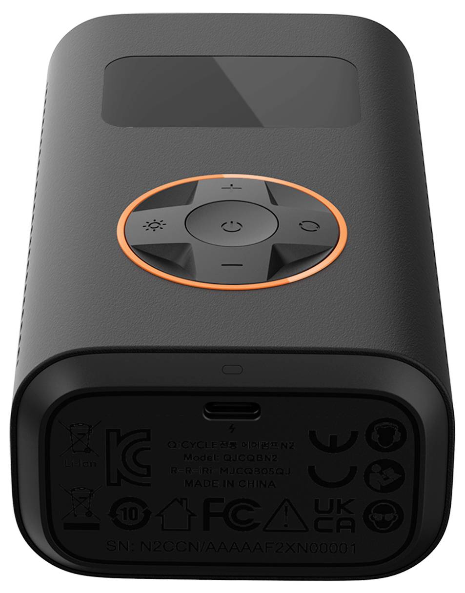 Tragbares schwarzes Gerät mit einer zentralen orangefarbenen Ringschaltfläche, die Energie- und Menüsymbole aufweist. Die Unterseite zeigt Regulierungssymbole und einen USB-C-Anschluss.