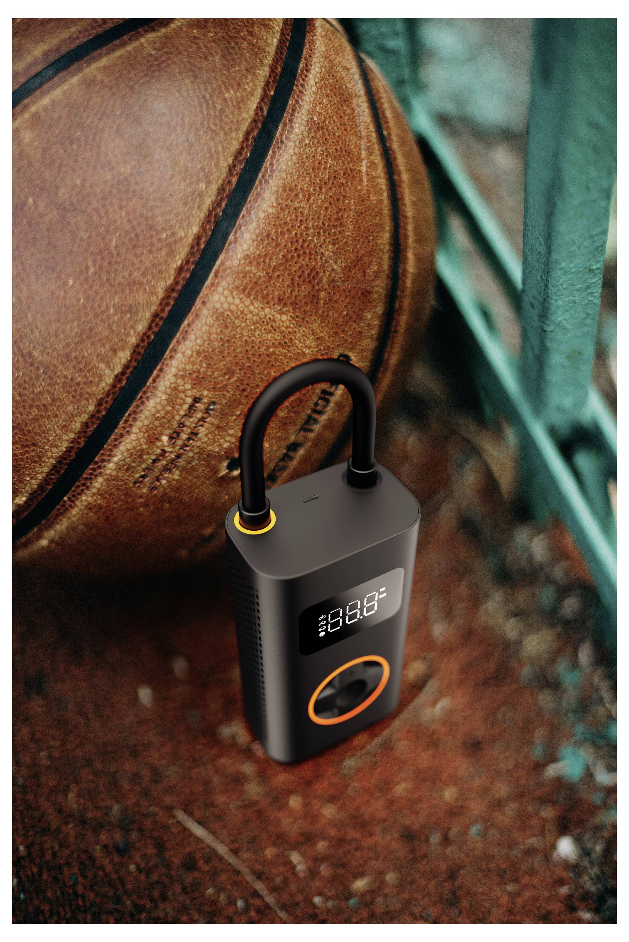 Eine tragbare Luftpumpe liegt neben einem Basketball auf dem Boden. Das digitale Display zeigt Zahlen und gibt den Betriebsstatus der Pumpe an.