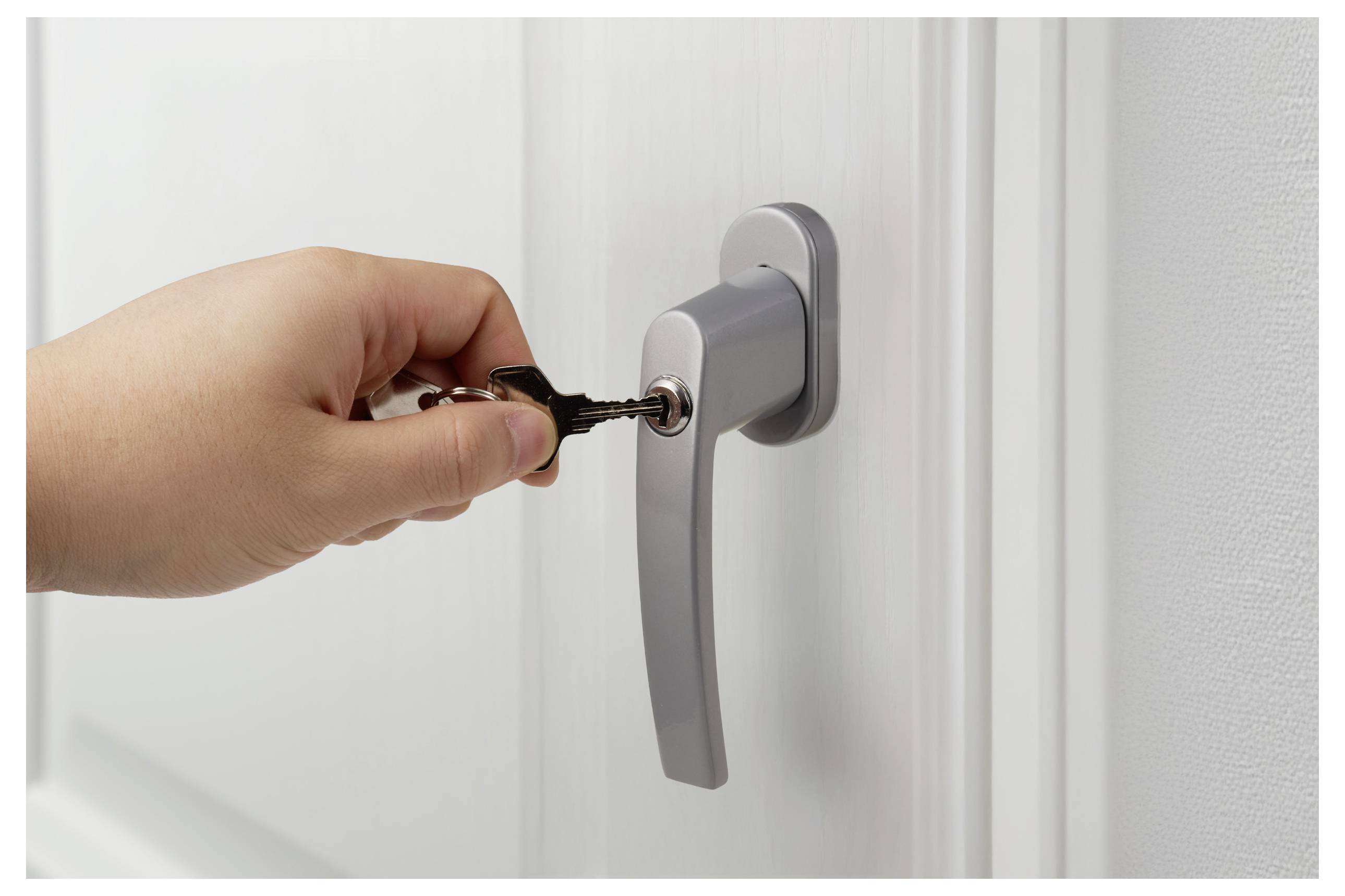 Eine Hand, die einen Schlüssel in das Schloss eines silbernen Türgriffs einführt und damit Zugang oder Sicherheit andeutet.