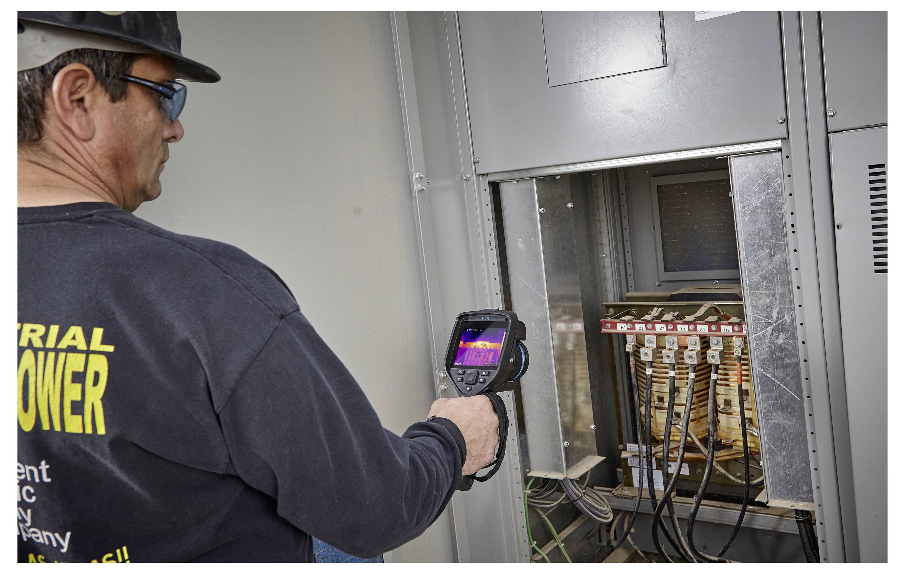 Ein Mitarbeiter verwendet eine Wärmebildkamera, um elektrische Komponenten zu untersuchen und dabei Temperaturunregelmäßigkeiten zur Sicherheit zu identifizieren.