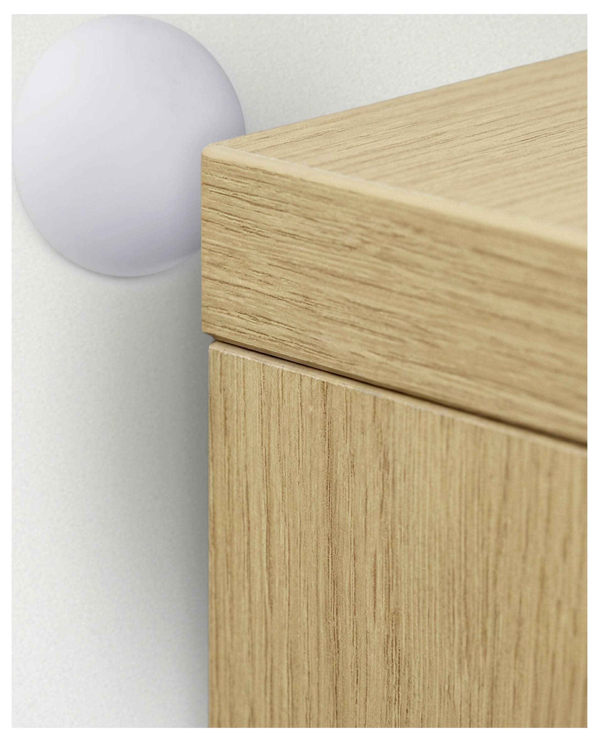 Ein rundes, weißes Wandpuffer schützt eine Tür eines hellholzfarbenen Schranks vor Kontakt mit der Wand.