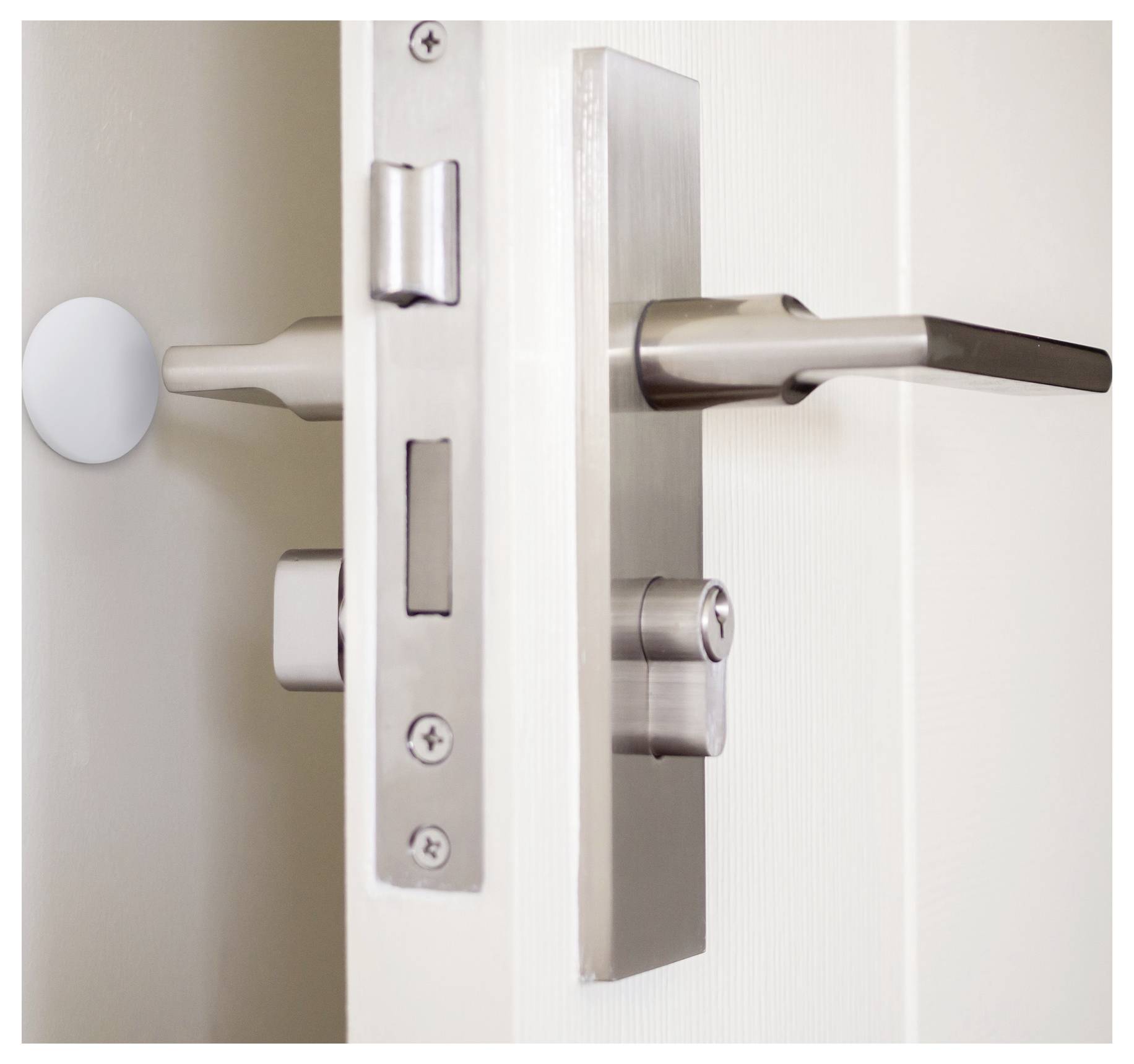 Ein Nahaufnahmebild einer teilweise geöffneten weißen Tür mit einem modernen metallischen Schloss und Griff, das die Mechanik und Details des Türrahmens zeigt.