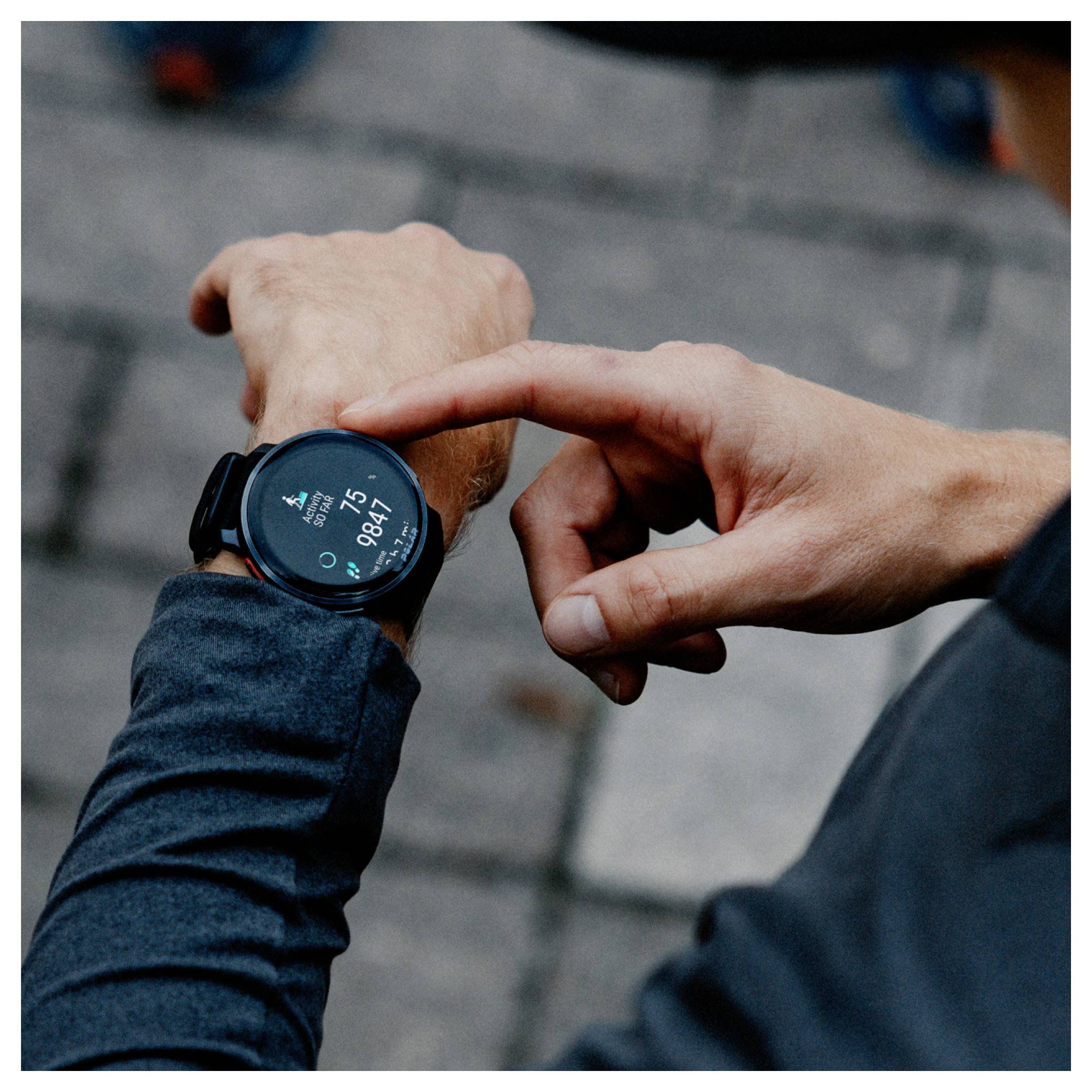 Eine Person mit dunklem Ärmel überprüft eine Smartwatch, die die Zeit '8:47' auf einem verschwommenen Steinpflaster-Hintergrund anzeigt.