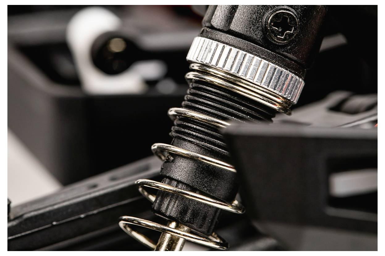 Nahaufnahme einer Metallfeder, die um eine schwarze mechanische Komponente gewickelt ist und den Fokus auf Maschinenteile oder industrielle Ausrüstung legt.