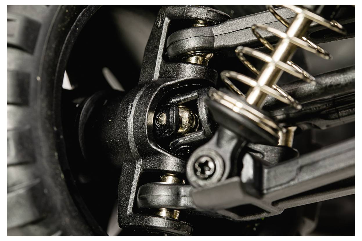 Nahaufnahme eines Fahrzeug-Federsystems, die Metallfedern und Bolzen zeigt, die mit einem Rad verbunden sind und technische Details der Konstruktion veranschaulichen.