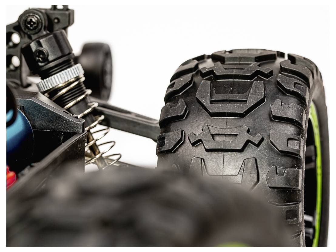 Nahaufnahme der Vorderradaufhängung und der Räder eines RC-Autos, die das Profil der Bereifung und die Federspule betont, wobei Haltbarkeit und Leistung im Fokus stehen.