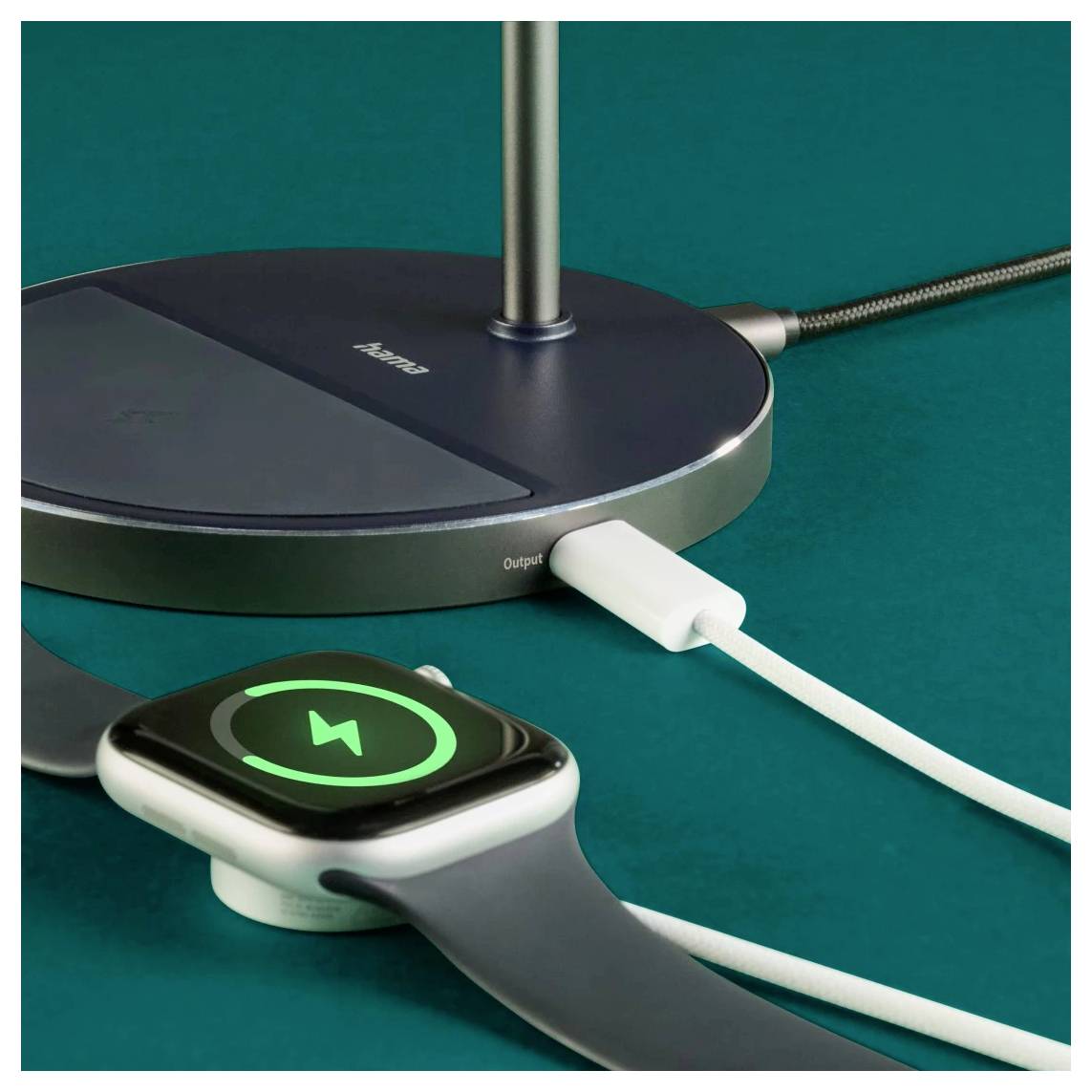 Eine Smartwatch auf einem Ladeständer zeigt ein Batteriesymbol mit einem Blitz, der einen laufenden Ladevorgang anzeigt, verbunden über ein USB-Kabel.