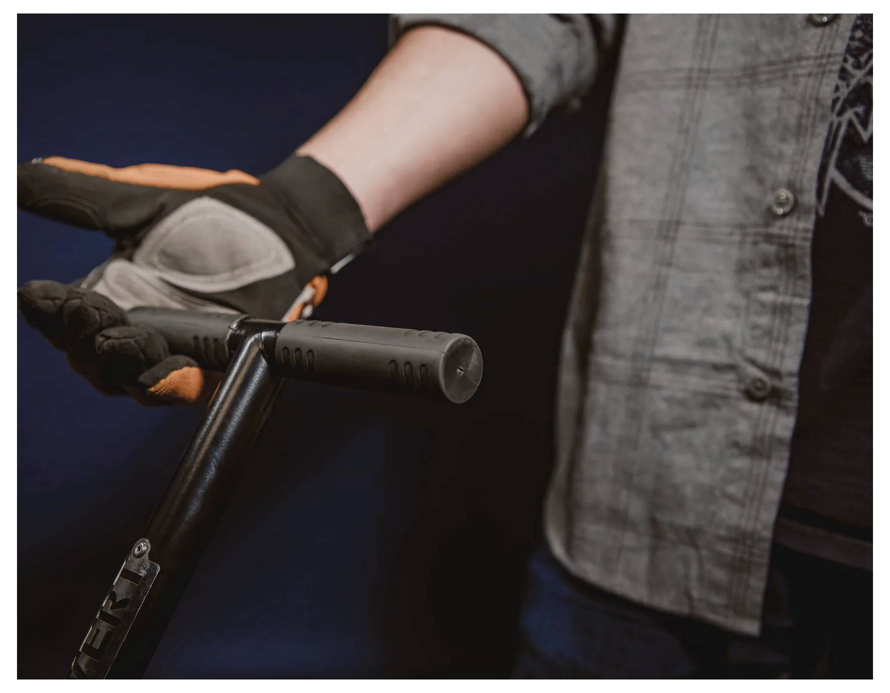 Eine Person mit Handschuhen streckt eine offene Hand neben dem Lenker eines Rollers aus und deutet damit eine Bereitschaft oder Einladung zum Mitfahren an.