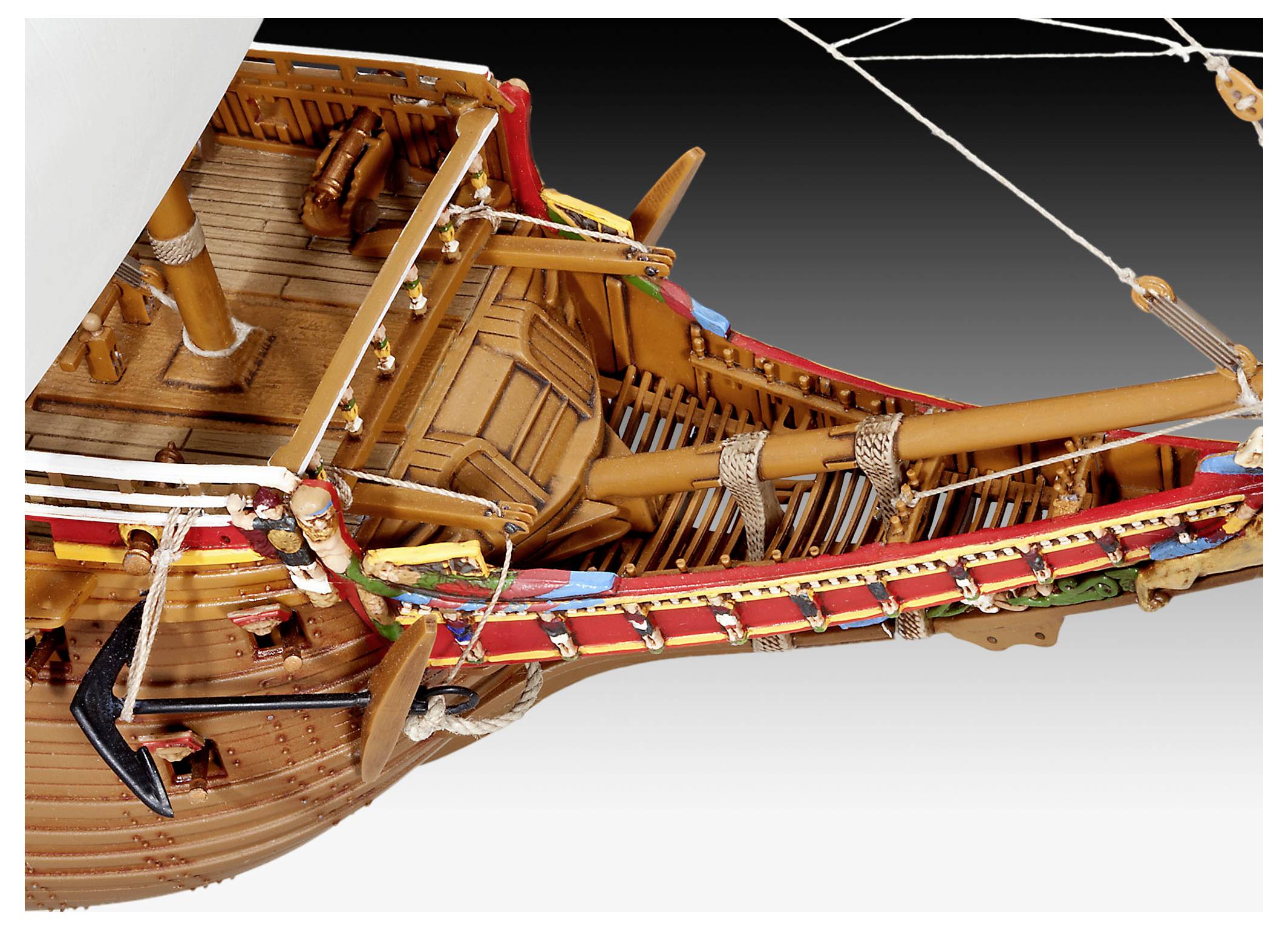 Modellschiff mit detaillierter und farbenfroher Bugsektion, mit Seilen, Holzelementen und aufwendiger Takelage vor einem Verlaufshintergrund.