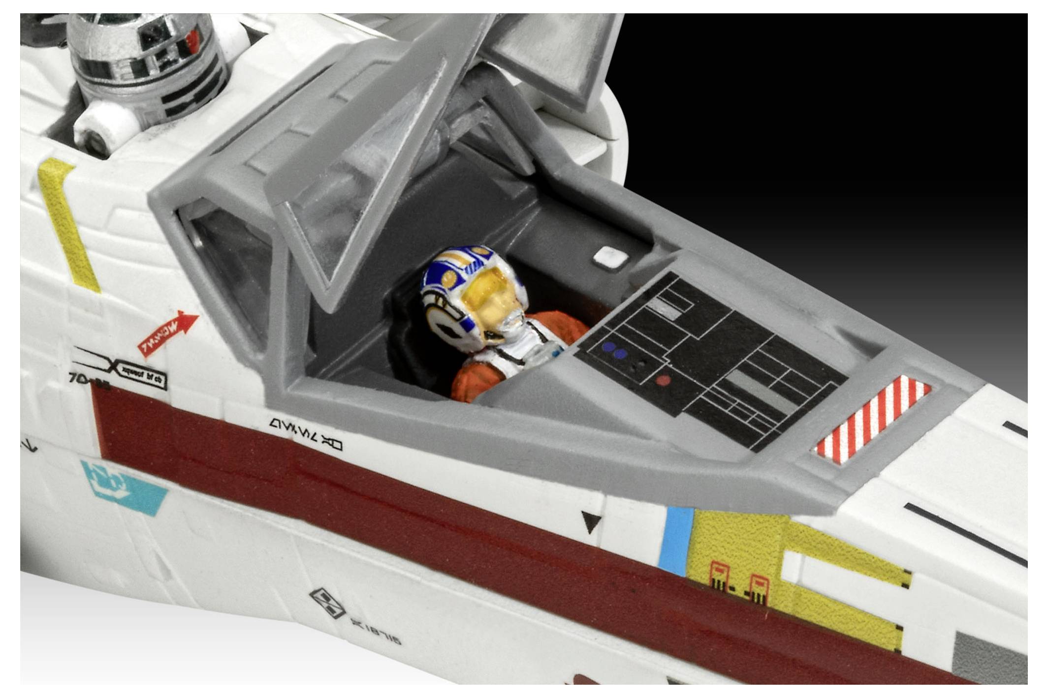 Eine Nahaufnahme des Cockpits eines Modellraumschiffs zeigt eine Figur eines Piloten in einer weiß-roten Uniform mit Helm, die darin sitzt.