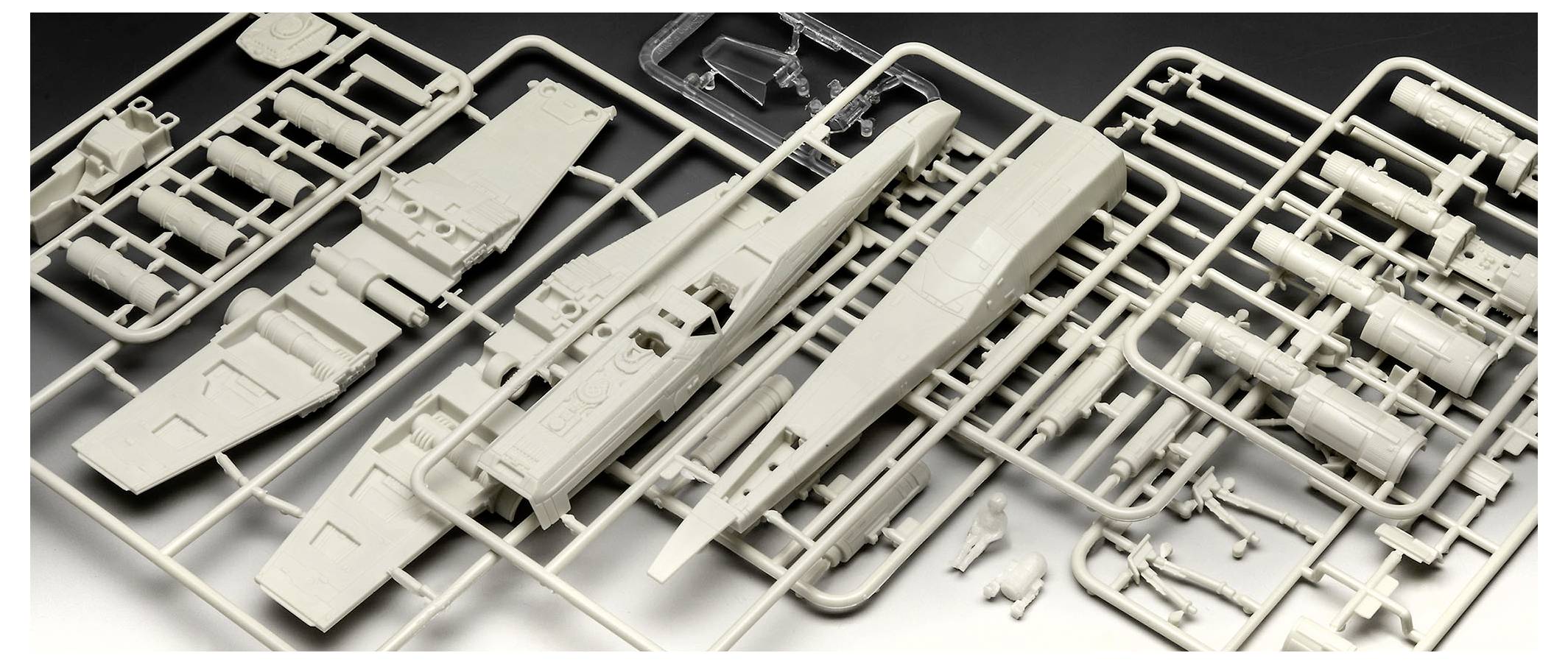 Kunststoff-Modellteile auf einem Angussblatt, einschließlich Flugzeugzelle und Flügel, auf einer dunklen Oberfläche ausgelegt, bereit zur Montage.