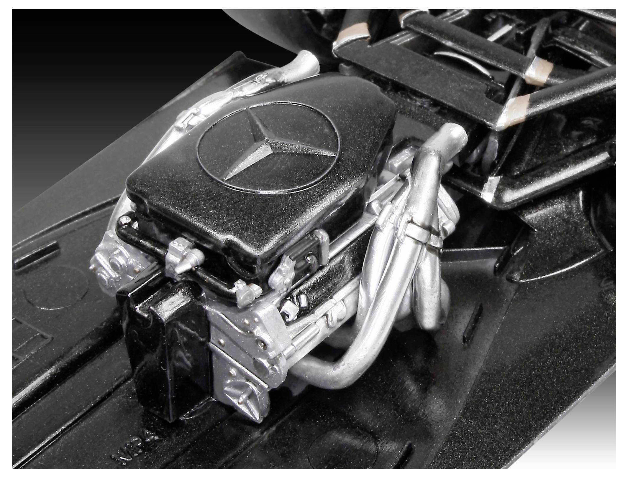 Eine Nahaufnahme eines detaillierten Modellmotors mit einem prominenten Logo in der Mitte, umgeben von metallischen Rohren und Komponenten.